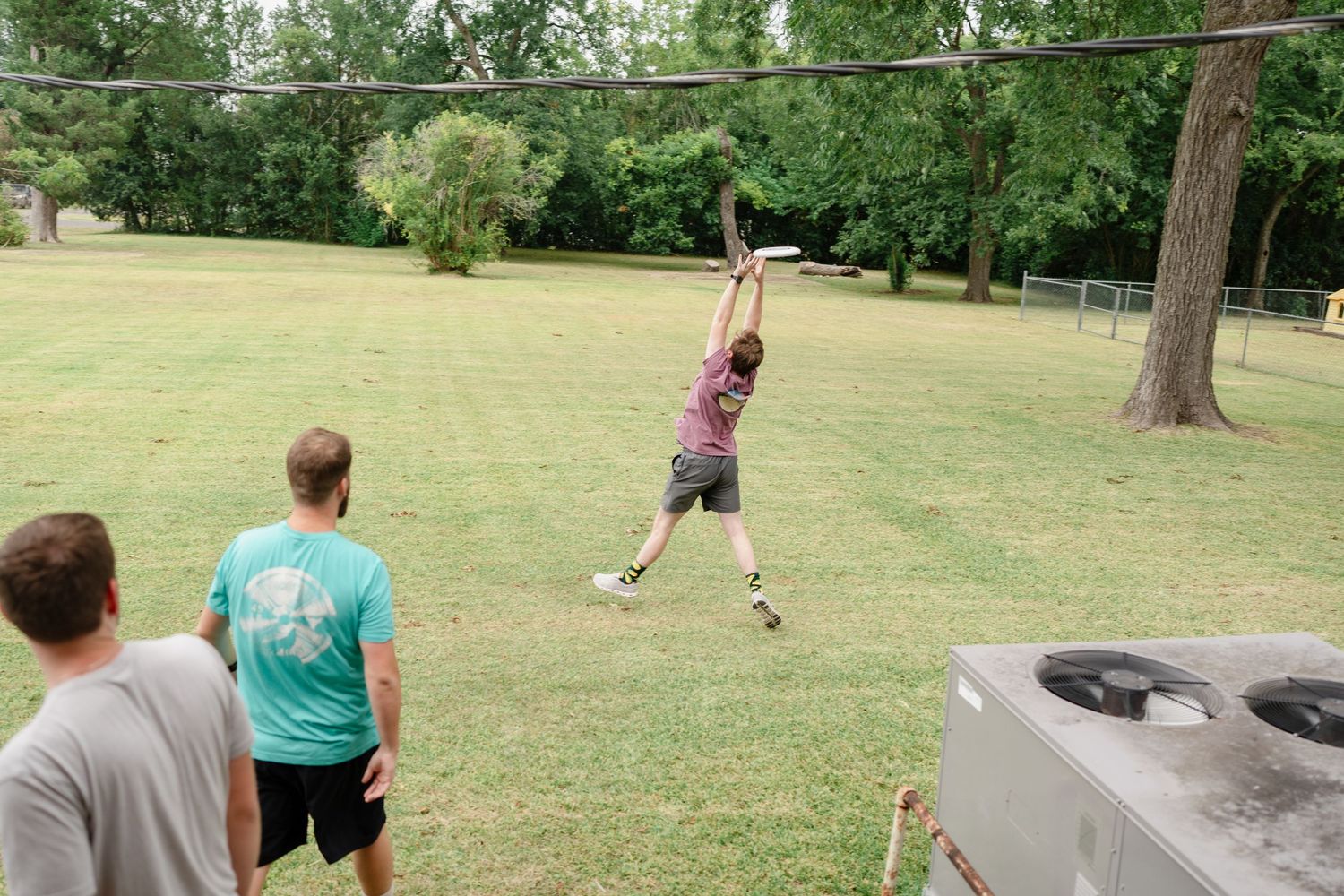 Group of people enjoying outdoor fitness activities with tires and exercises in a grassy park setting.