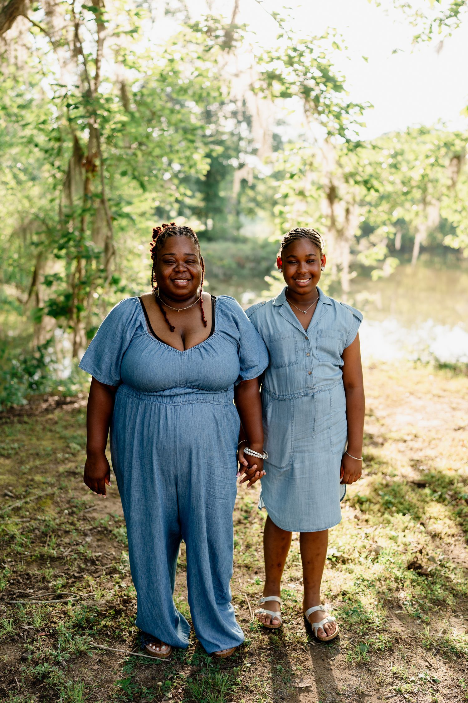 Two people in coordinating blue outfits share joyful smiles during an outdoor photo session.