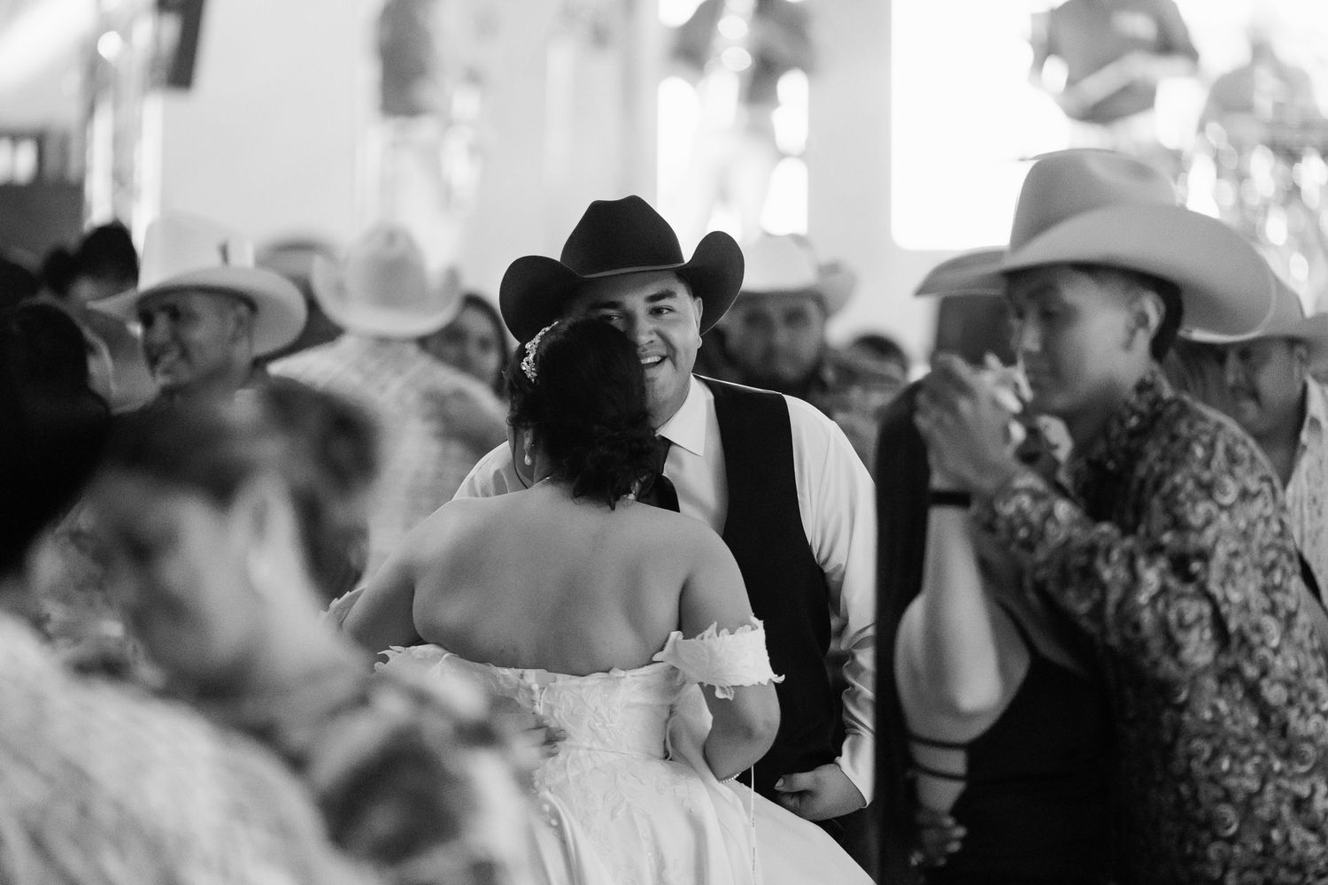 Wedding guests in cowboy hats socialize during a western-themed celebration.