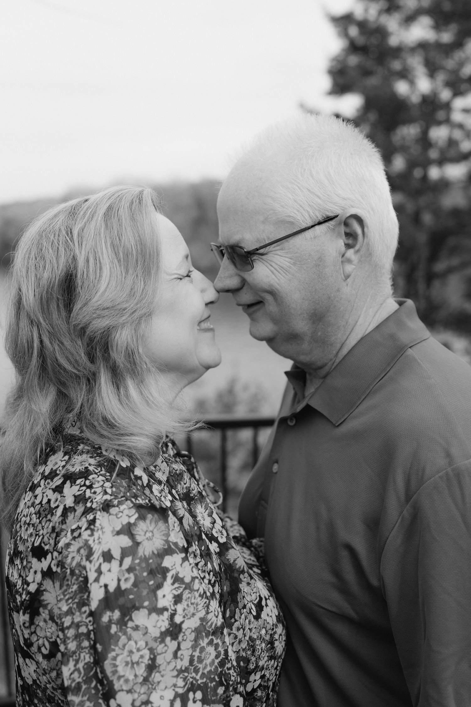 Black and white portrait of a smiling older couple gazing lovingly at each other outdoors.