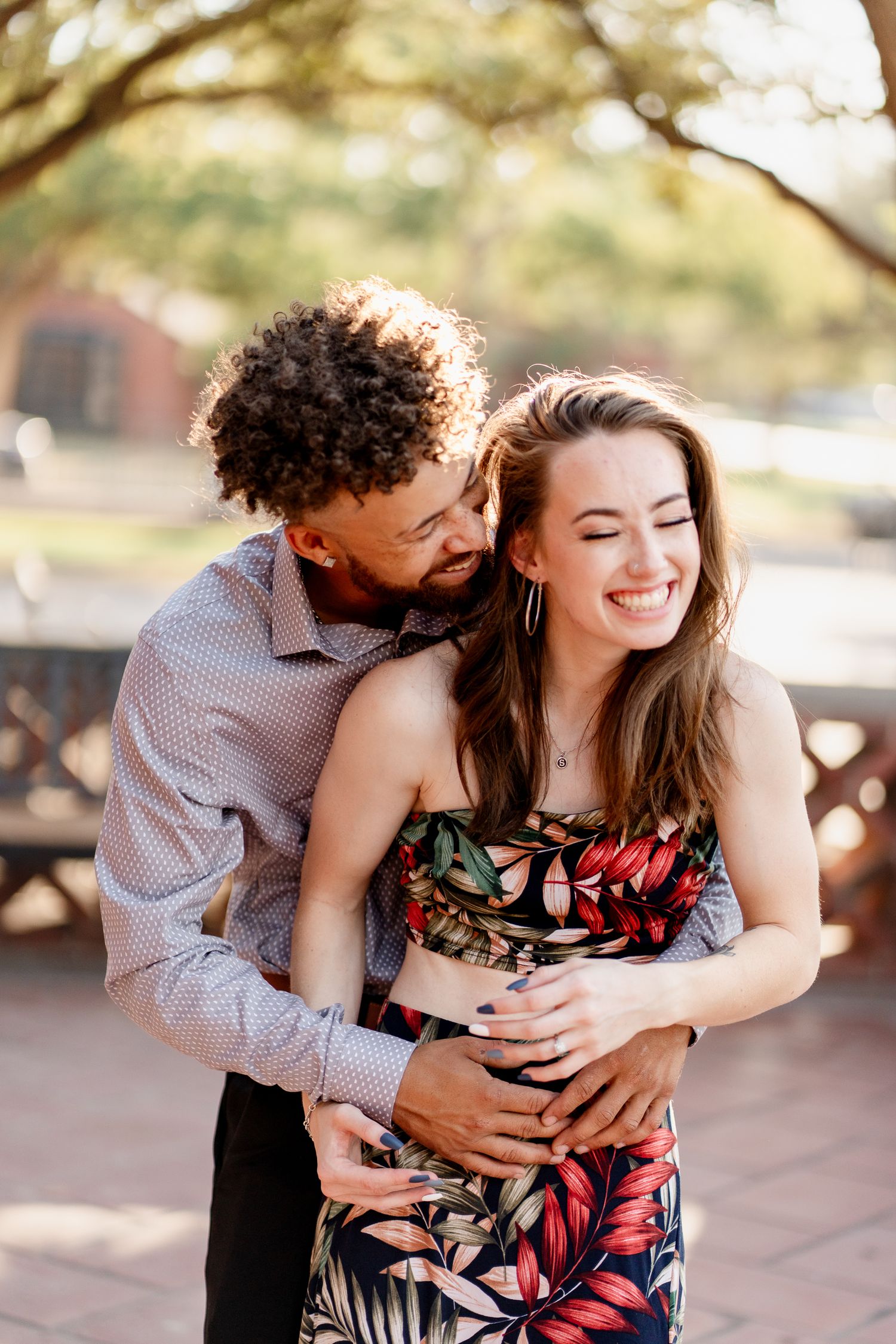 A couple embraces while laughing during their romantic outdoor photoshoot.