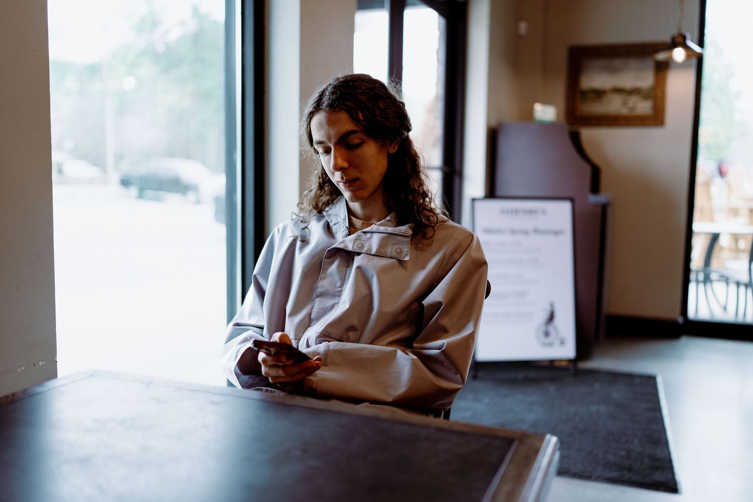Indoor candid shots showing someone looking at phone near large windows.