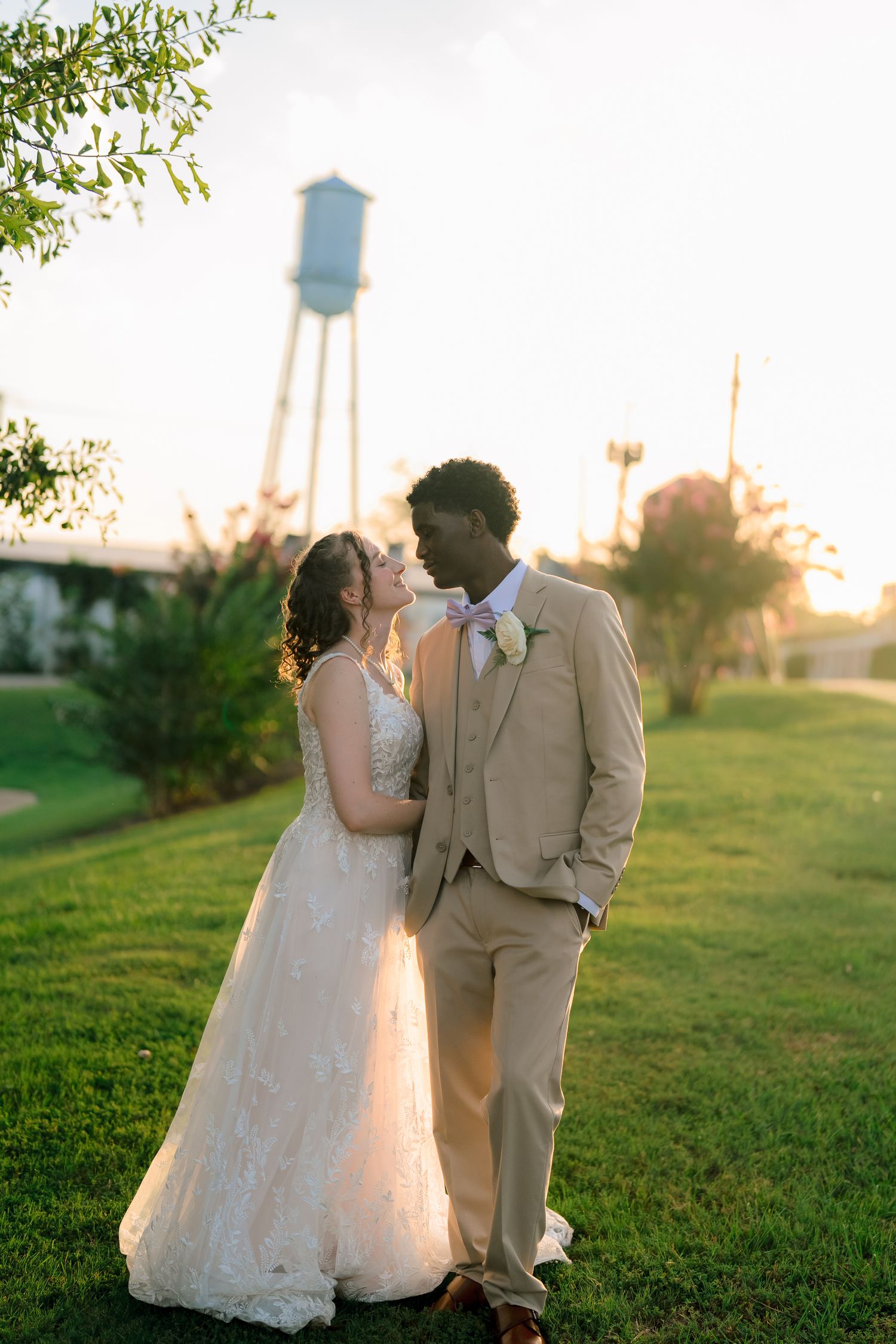Bride and groom share an intimate moment gazing at each other in warm sunset light outdoors.