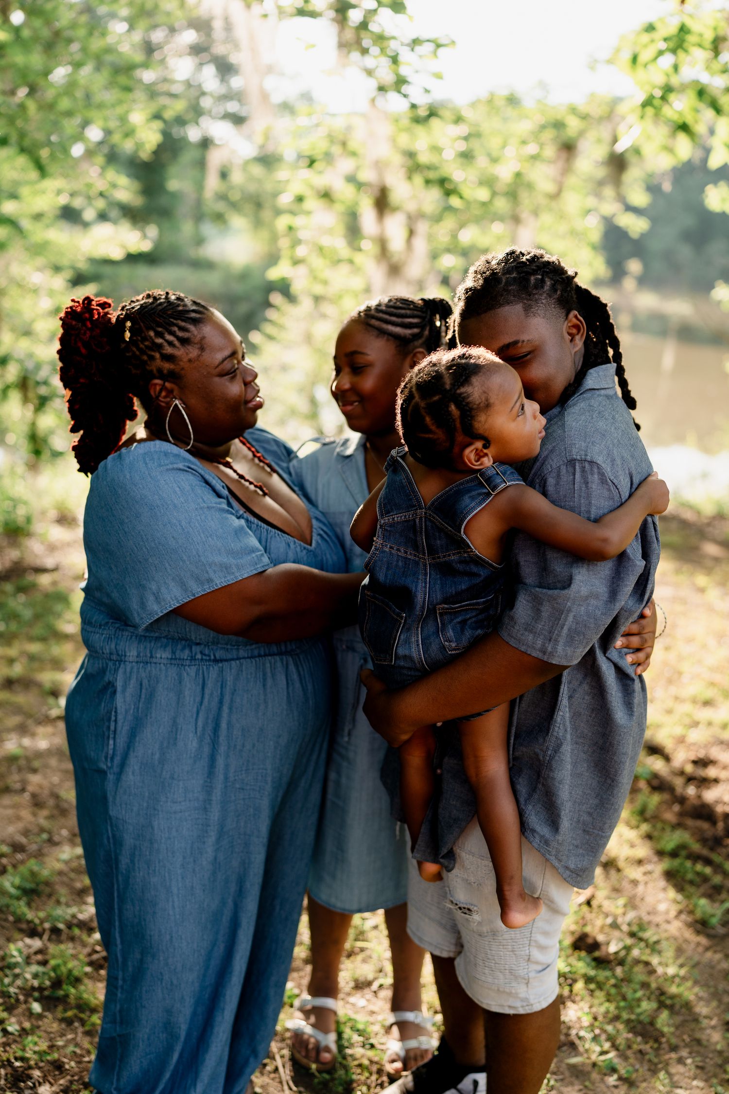 Candid moments of family hugging and laughing together in matching blue outfits by the water.