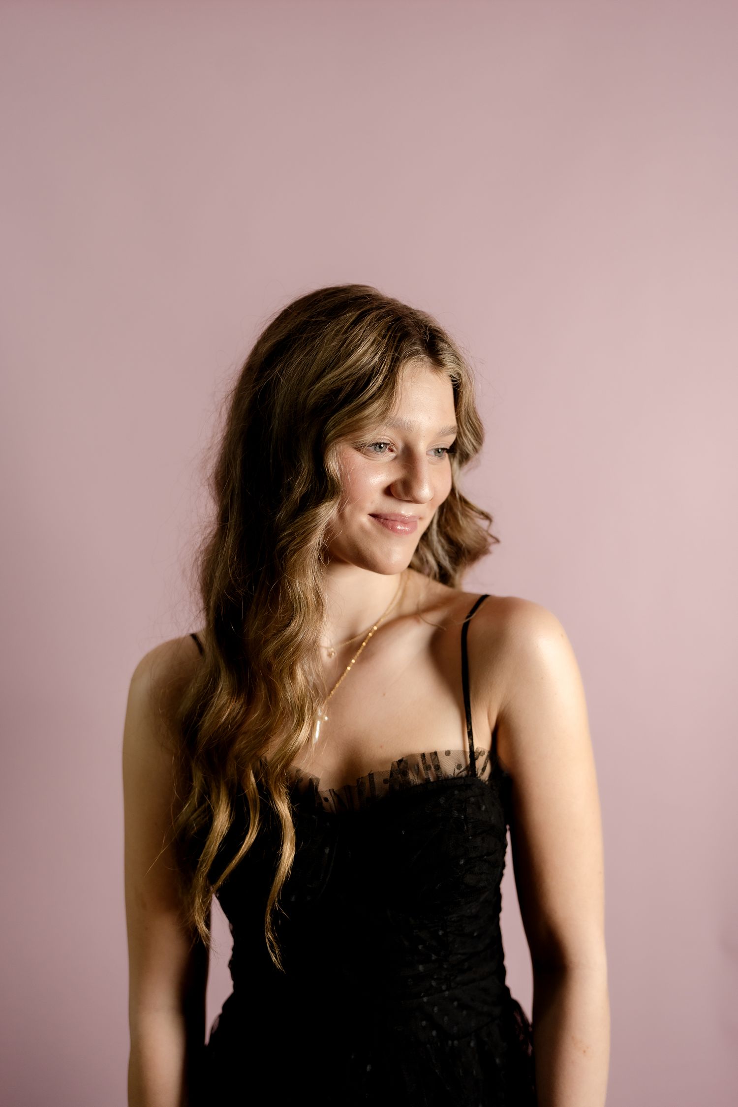 Artistic fashion portraits showcase a black dress against a soft pink backdrop.