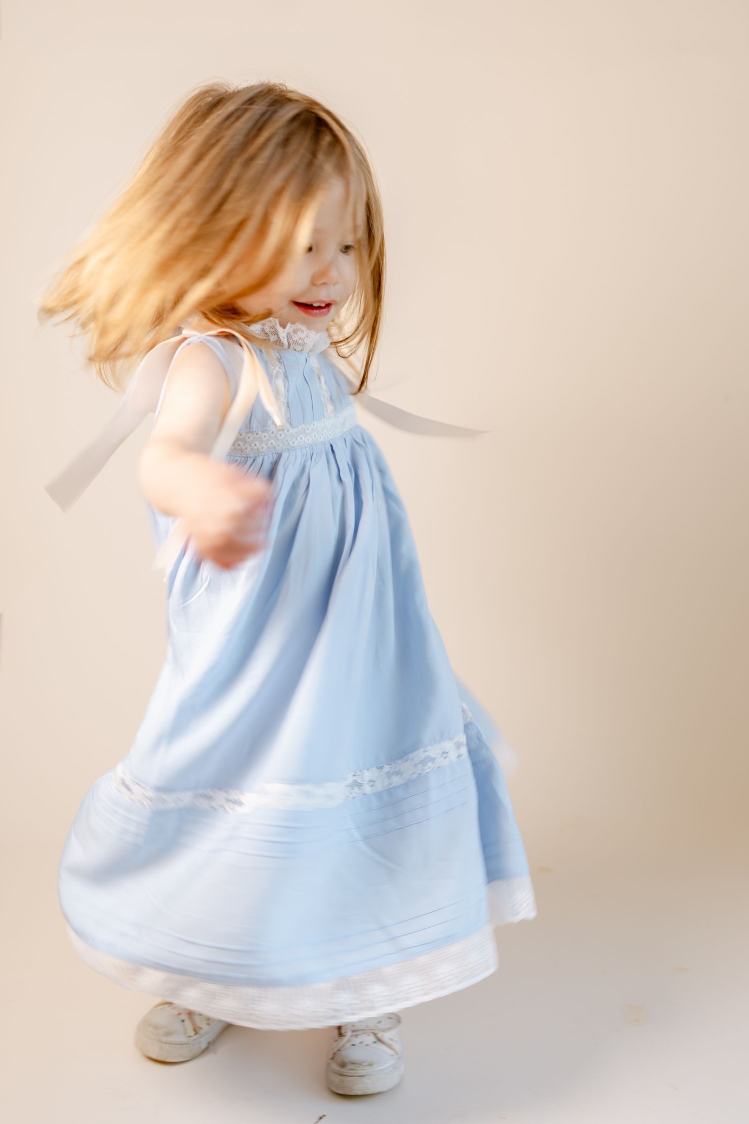 A flowing light blue dress with white trim twirls gracefully against a neutral backdrop.