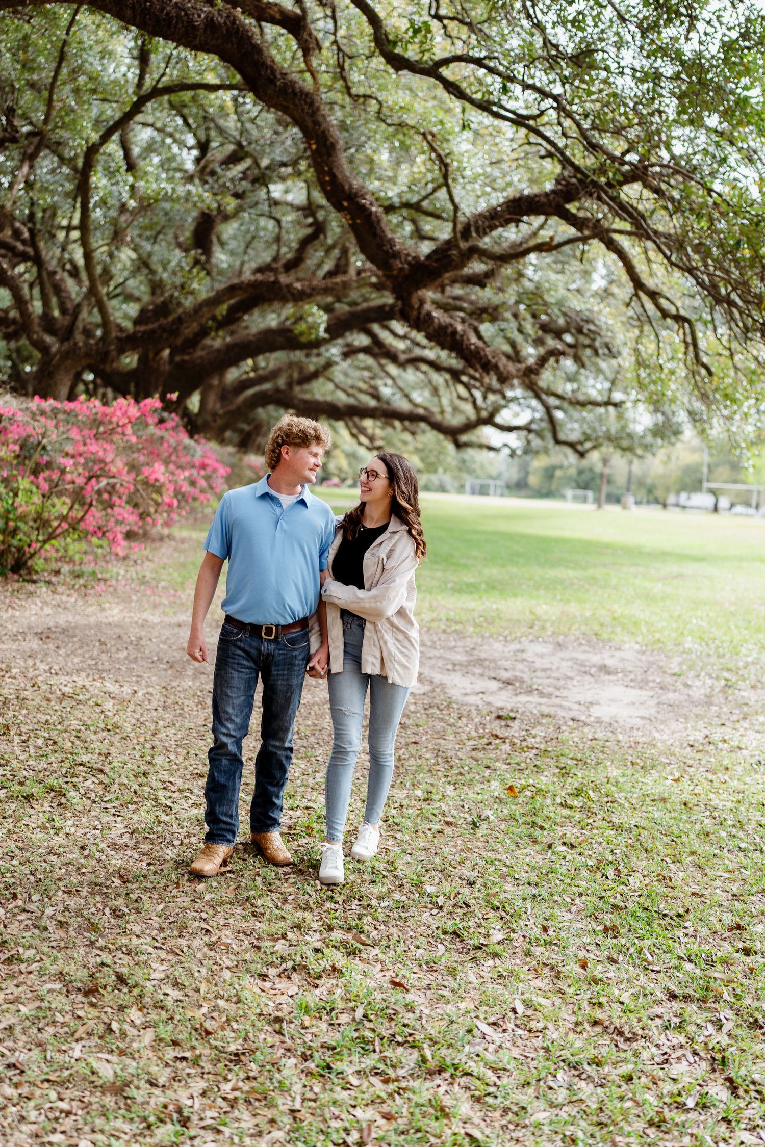 Couple enjoying moment together under large oak trees with blooming azaleas.
