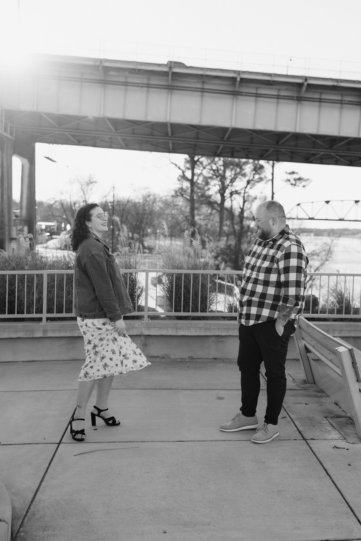 A couple sharing a romantic moment while sitting on a concrete surface during a photo shoot.