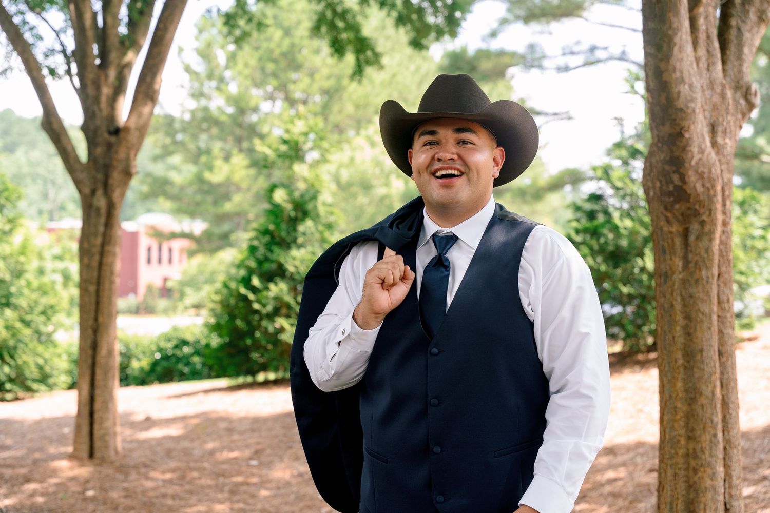 A couple in formal western attire poses together under shady trees for a series of outdoor portraits.