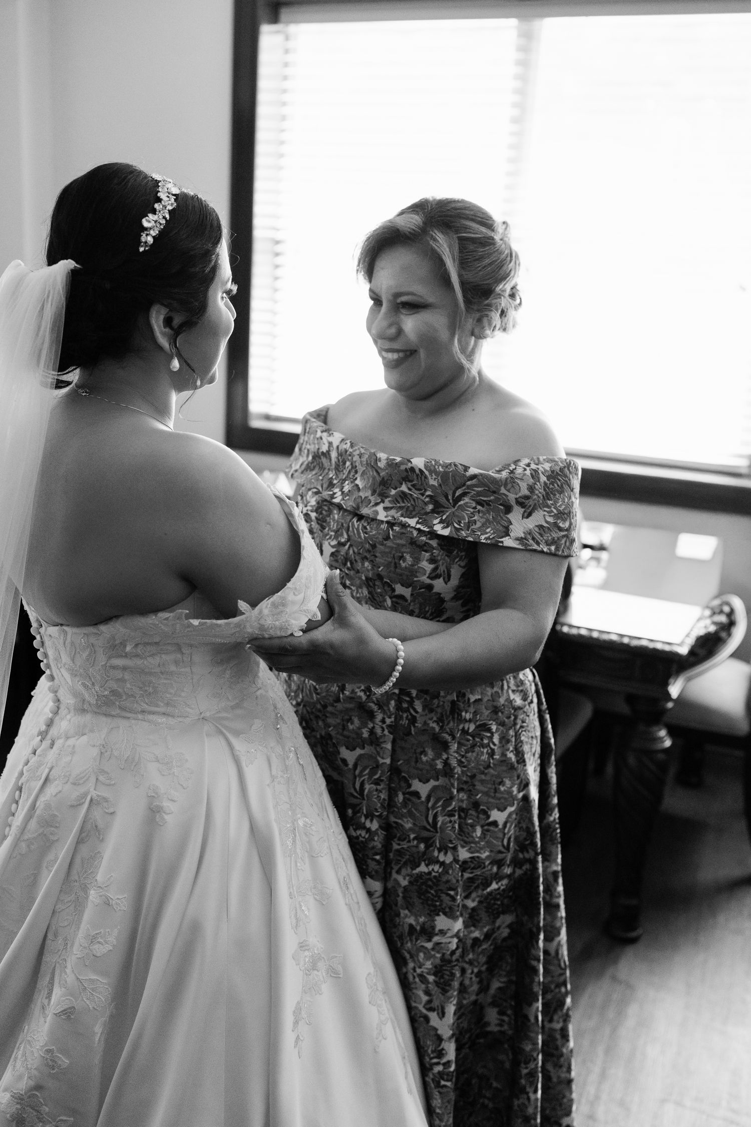 Black and white photos show the process of helping someone get dressed in a wedding gown.
