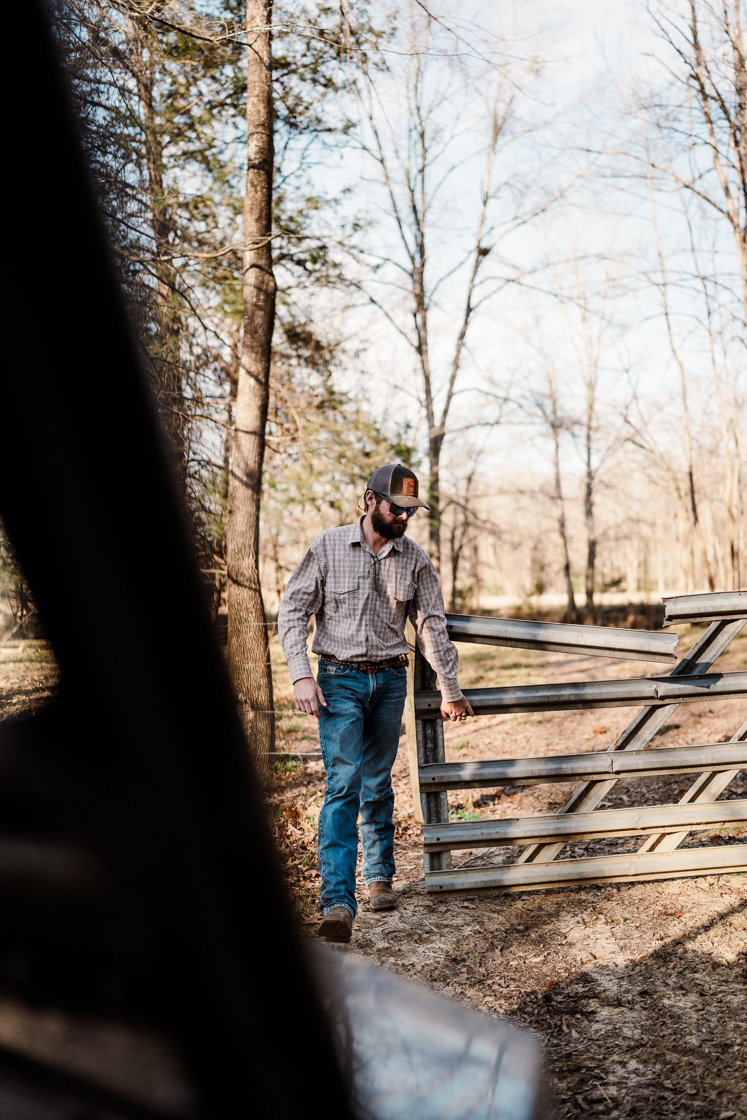 Someone tends to a rustic wooden split-rail fence on a farm property.