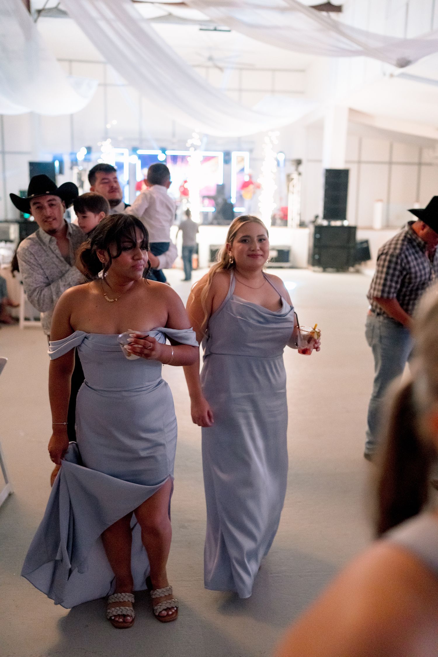 Wedding reception guests dancing and socializing in a white draped venue.