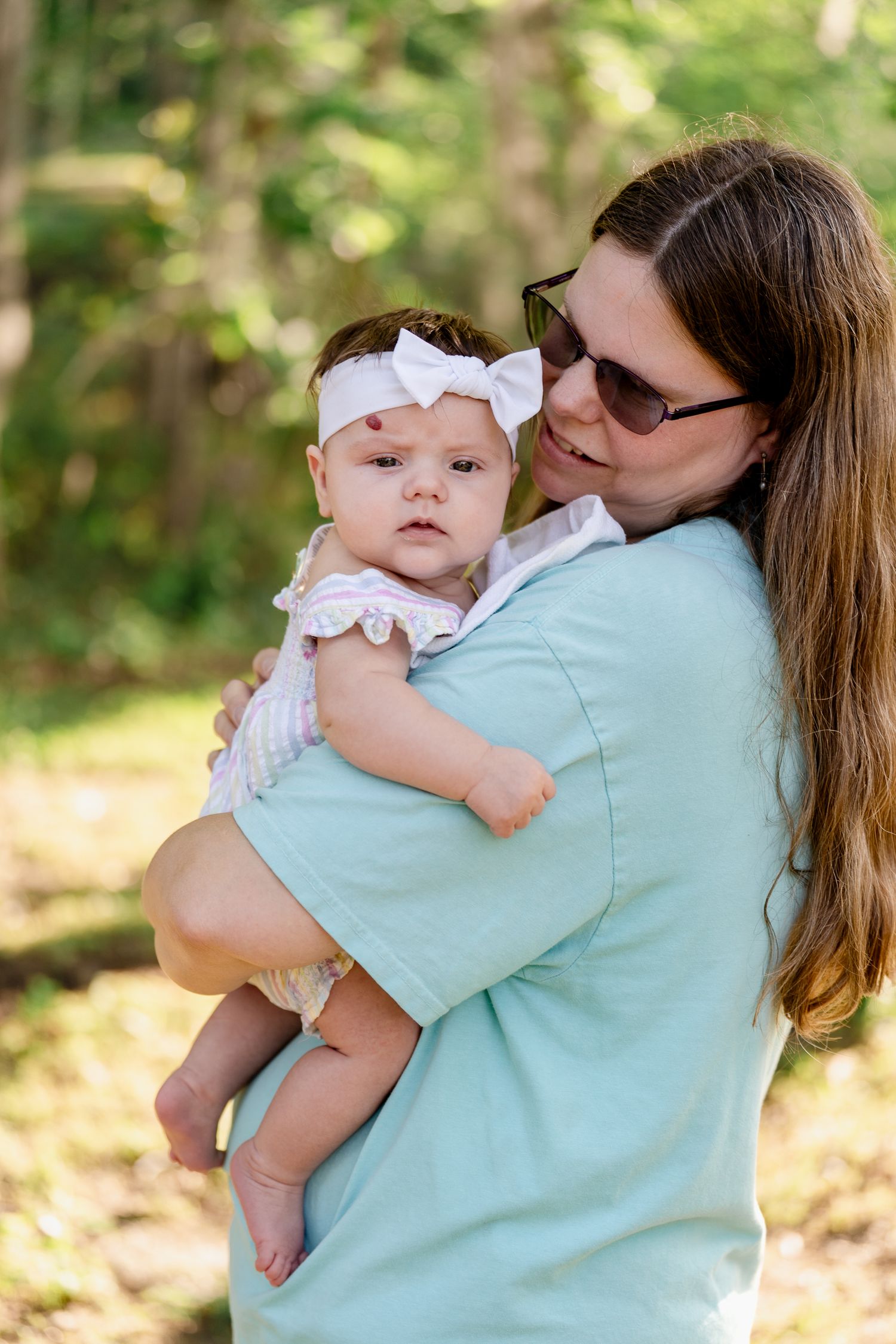 Close-up shots of mother and baby sharing tender moments while wearing matching mint blue shirts outdoors.