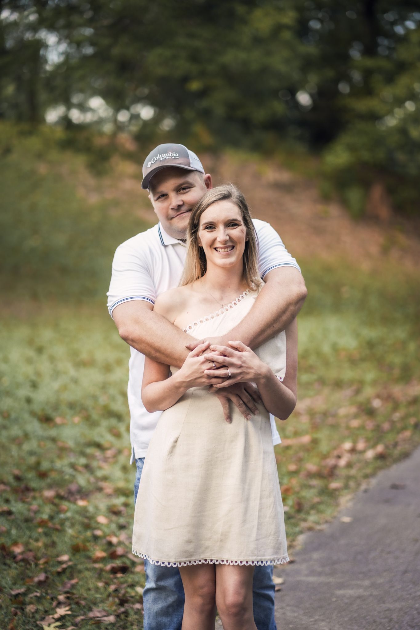 A couple embraces while taking casual photos in a natural outdoor setting.