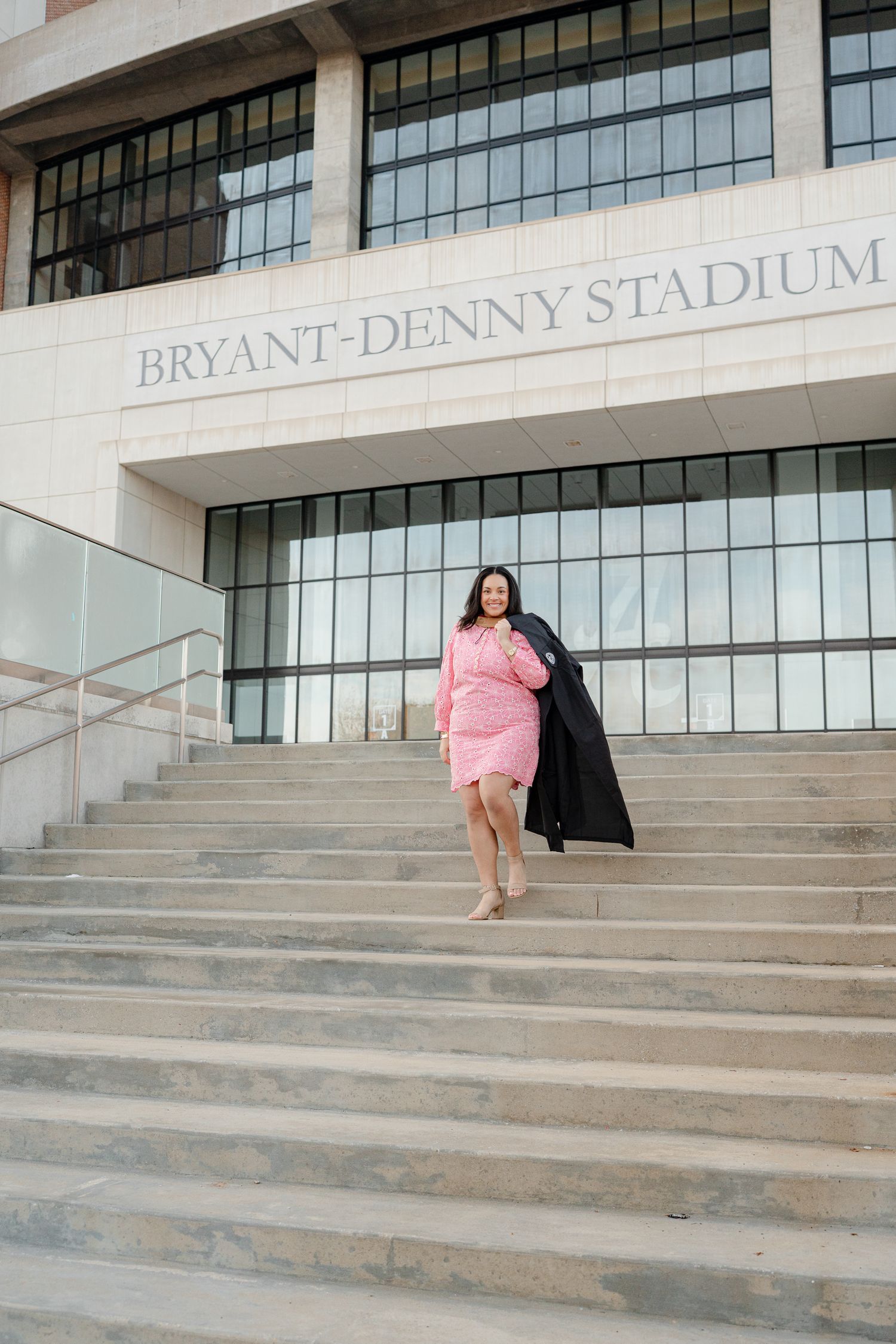 Multiple shots of a graduation photoshoot on the steps of Bryant-Denny Stadium with pink dress and black gown.