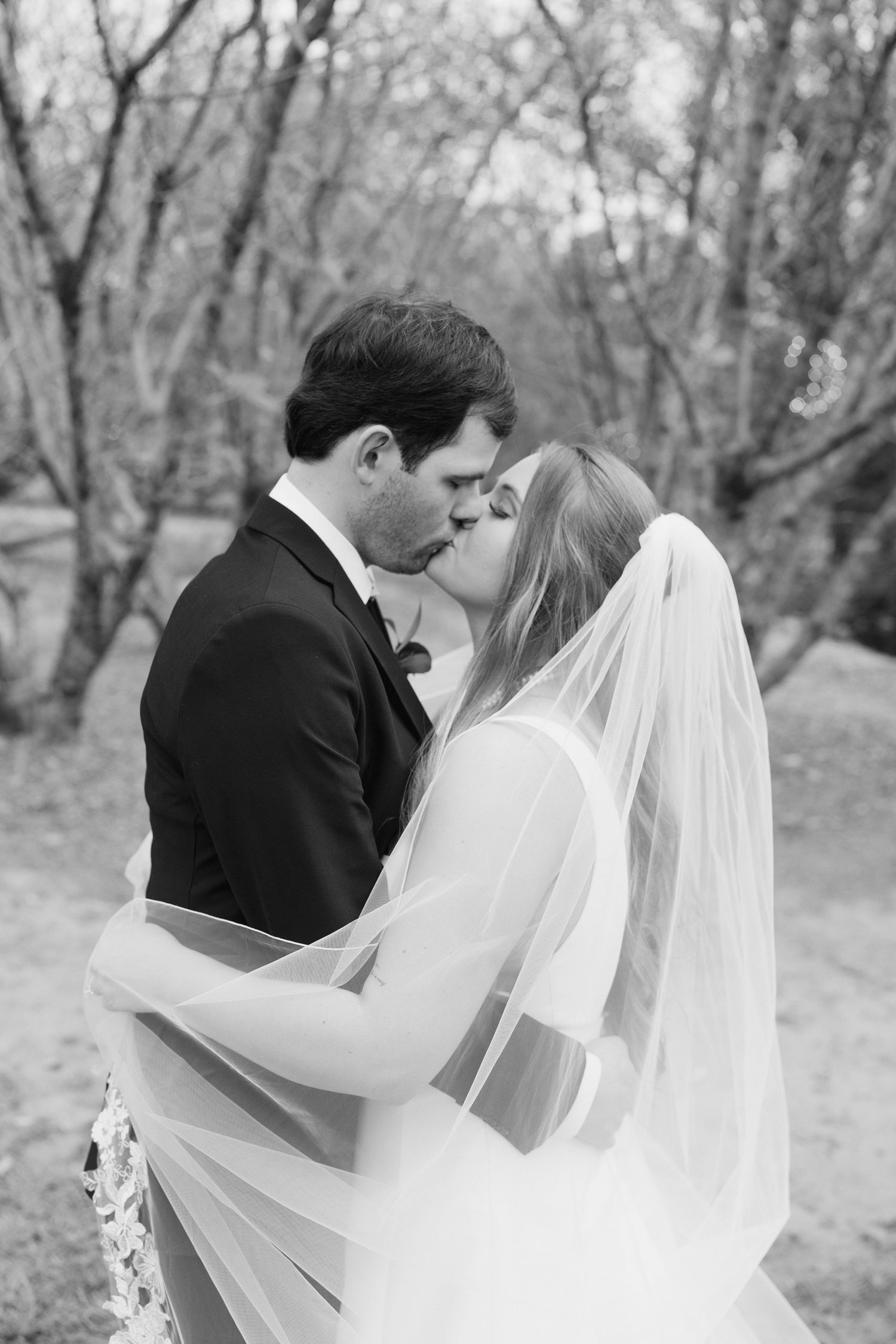 Black and white romantic wedding photos capturing intimate moments between newlyweds in a natural outdoor setting.