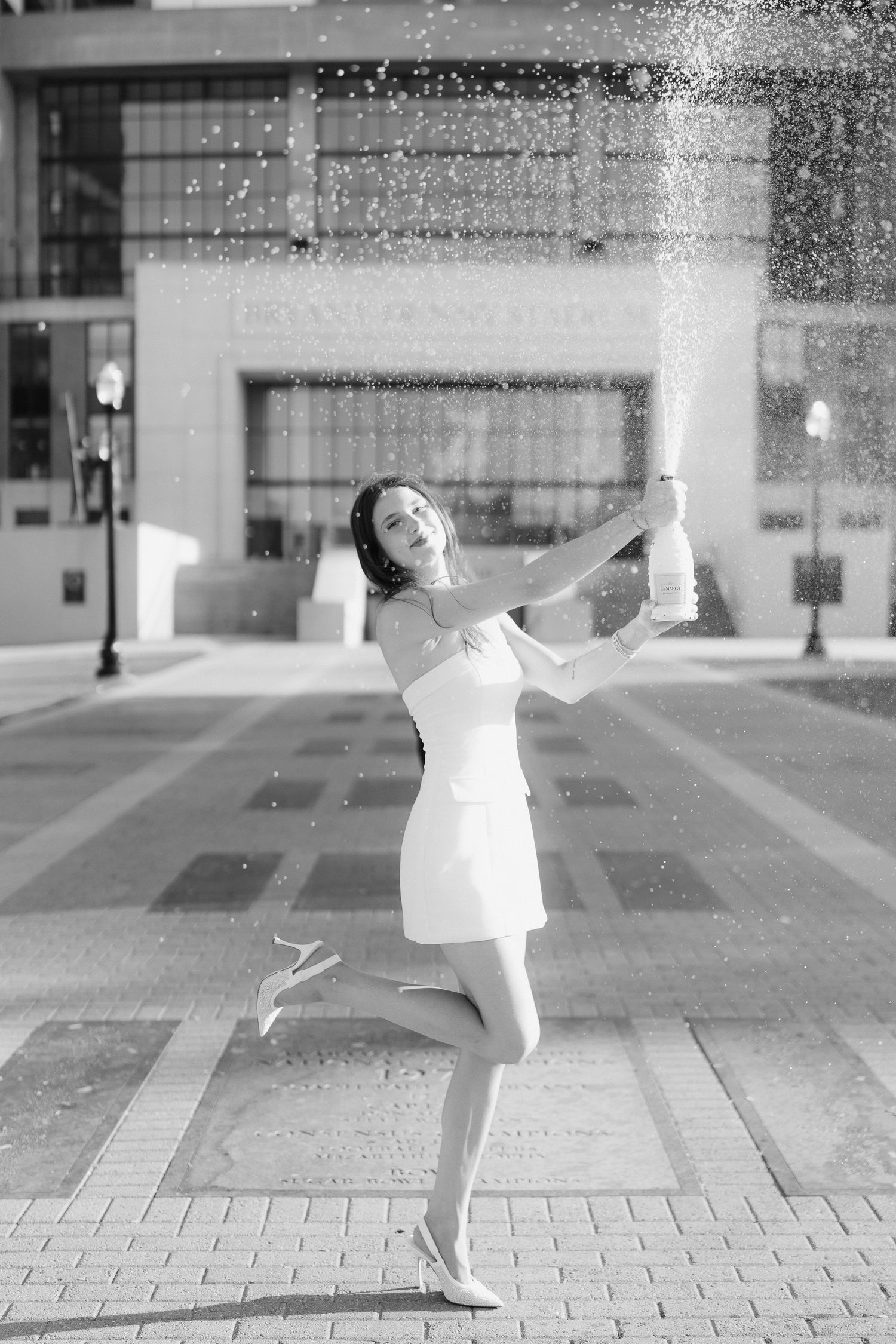 A sequence of black and white photos showing a ballet dancer performing graceful moves on a paved courtyard.