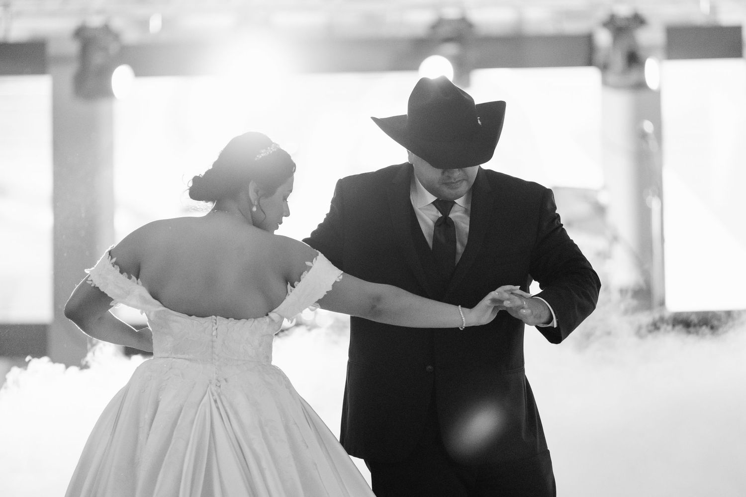 Black and white photo of a wedding party dancing and celebrating at an elegant reception venue.