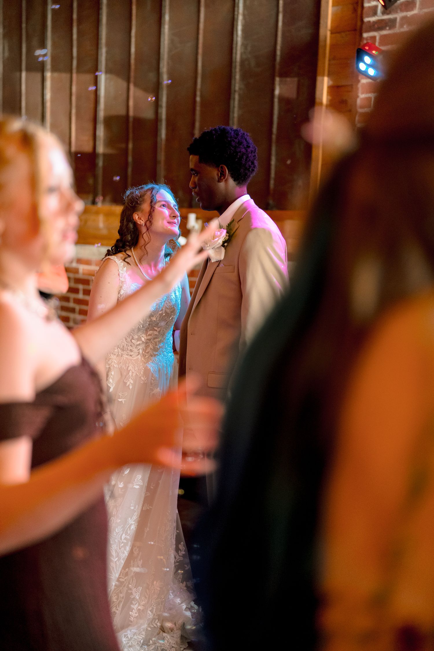 Interracial newlyweds share first dance together at elegant wedding reception in brick venue.