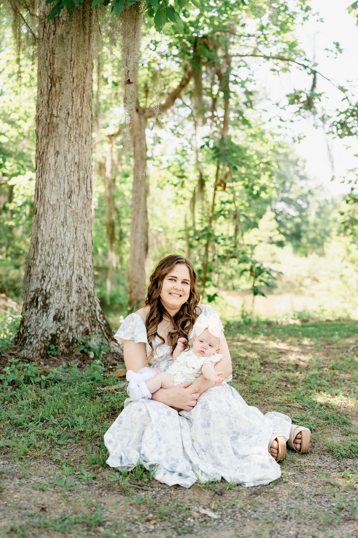 A peaceful outdoor portrait in a wooded setting with filtered sunlight through the trees.