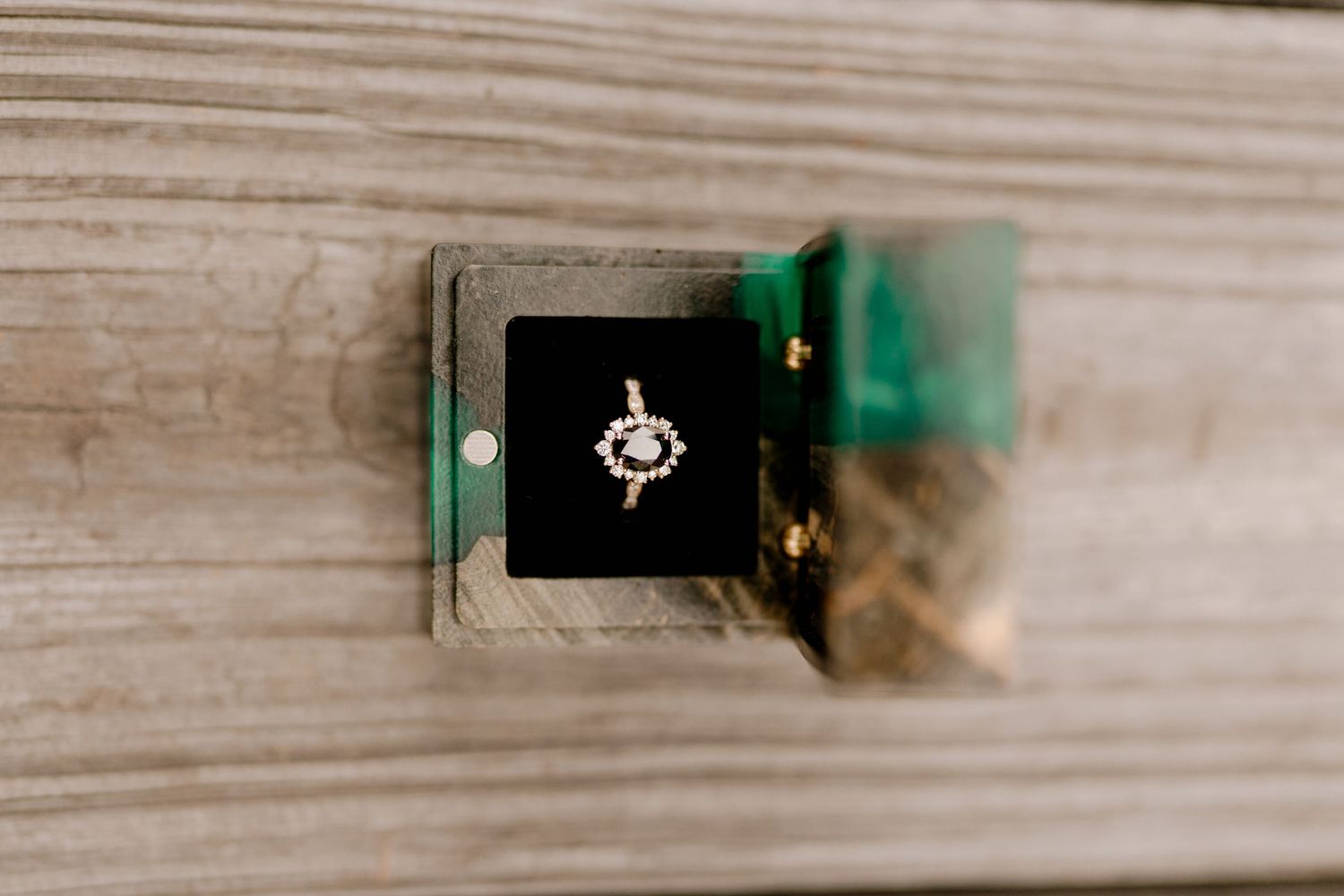 Close-up sequence of an engagement ring against a light wood grain background.