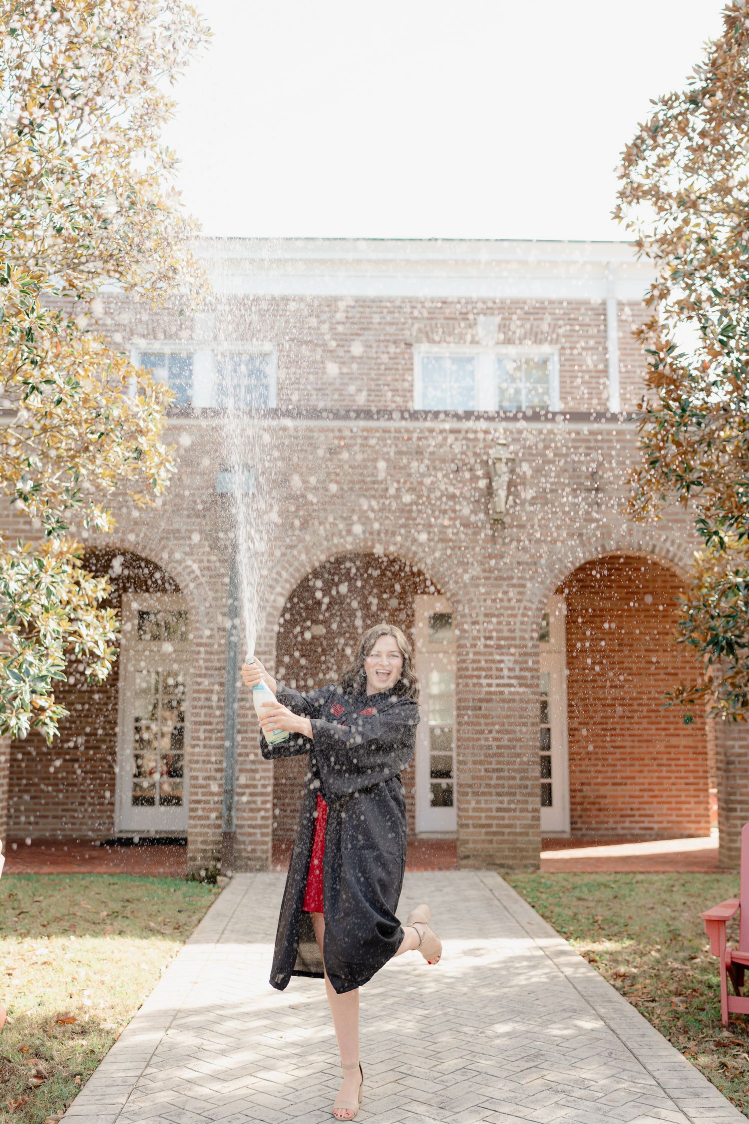 Person in black jacket spins joyfully on a brick patio with autumn leaves falling around them.