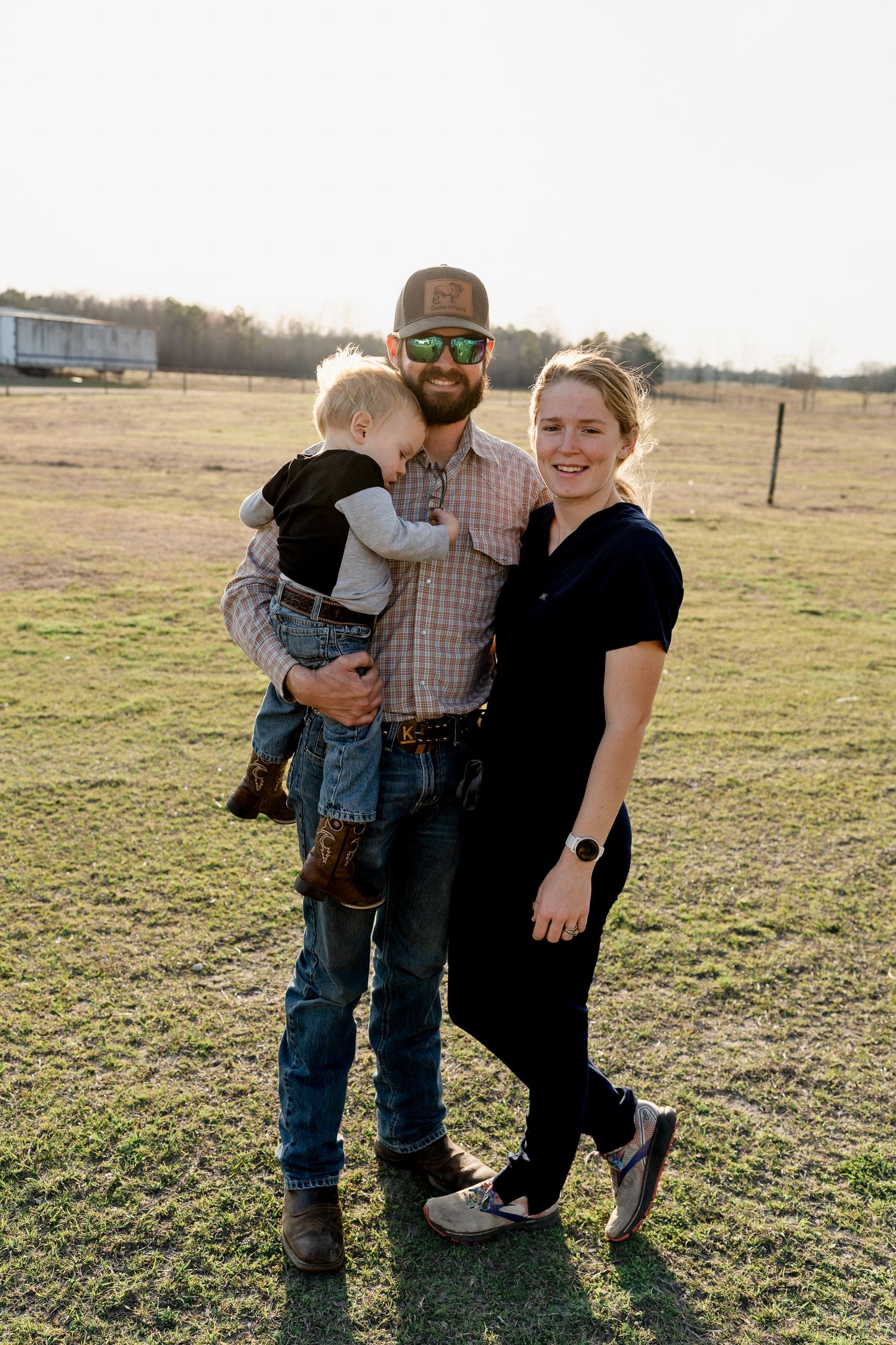 A family stands together in an open field during golden hour.