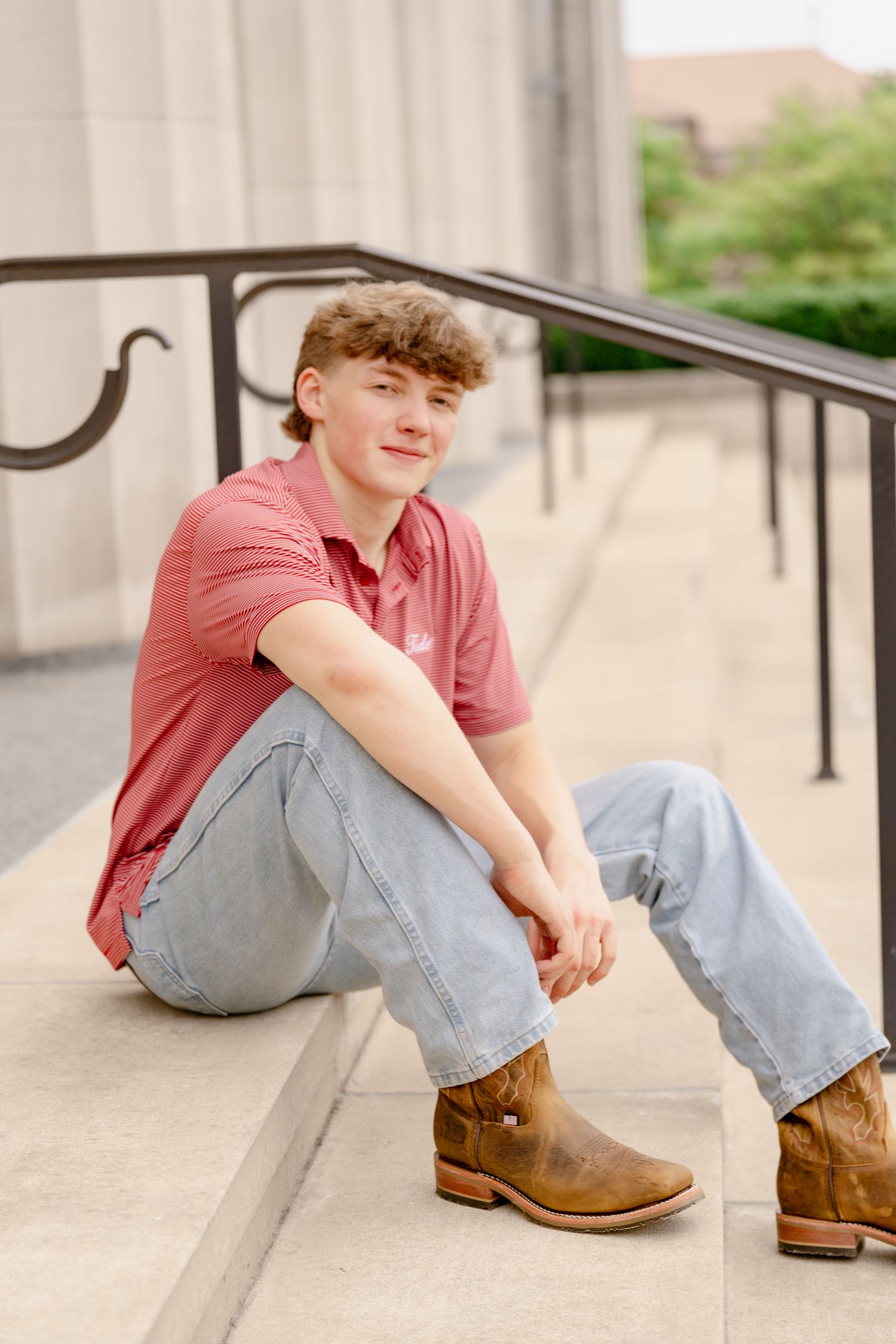 Casual portrait sitting on stone steps wearing boots and light wash jeans.