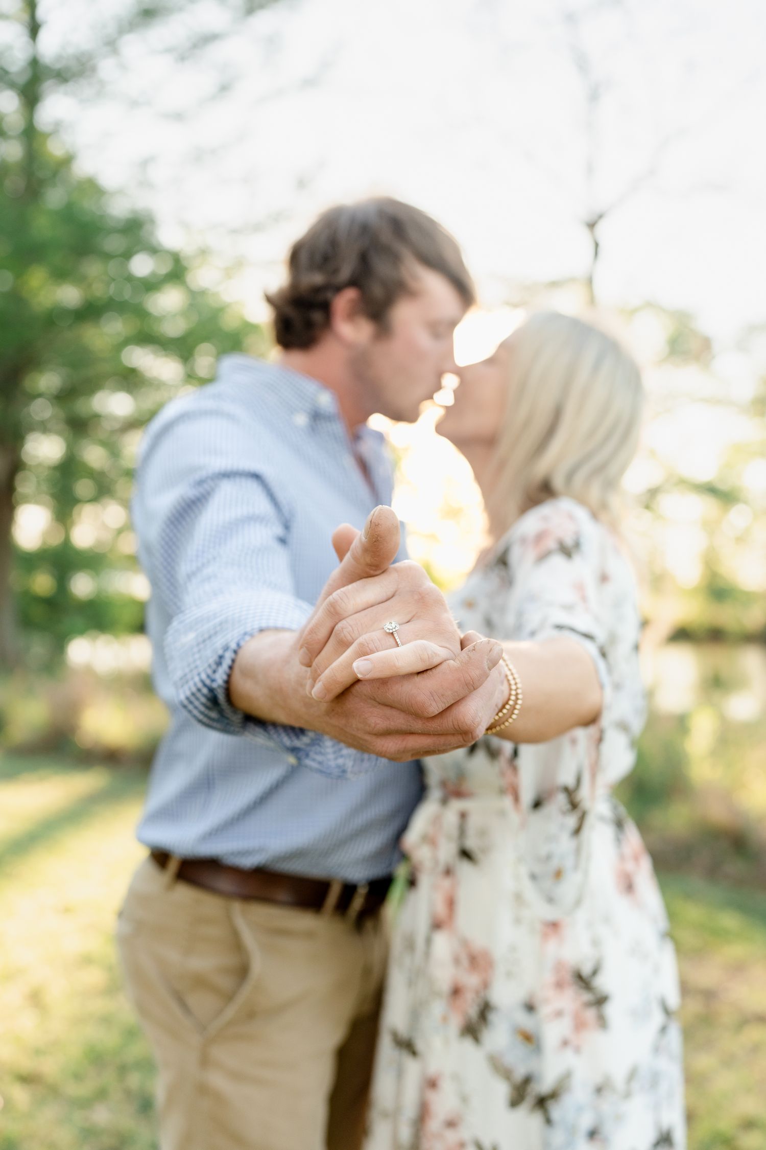 A romantic moment captured as a couple dances in a sunlit forest setting.