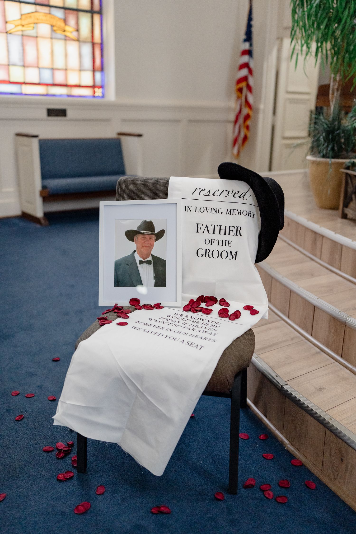 Reserved seating sign for groom's father with red rose petals on church steps.