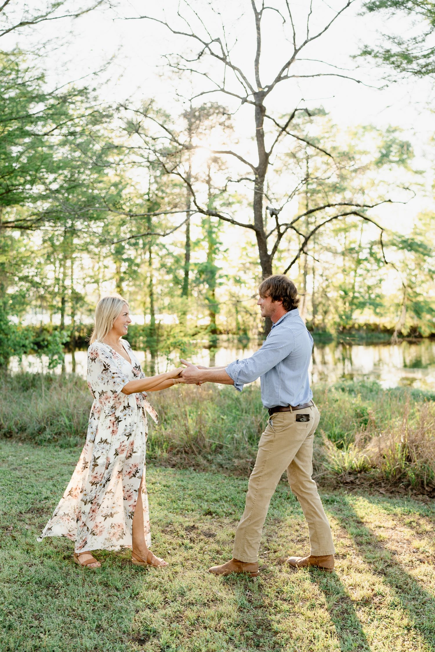 Dancing couple in coordinated outfits enjoying a tender moment by a lake.