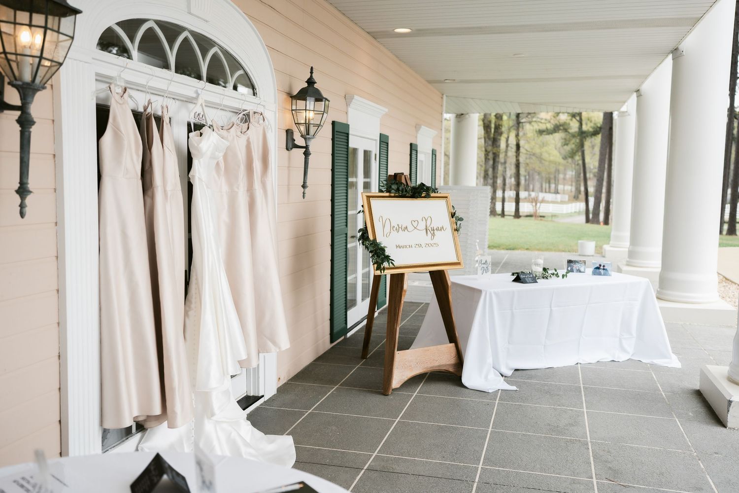 Wedding dresses displayed on outdoor porch with welcome sign and white linens.