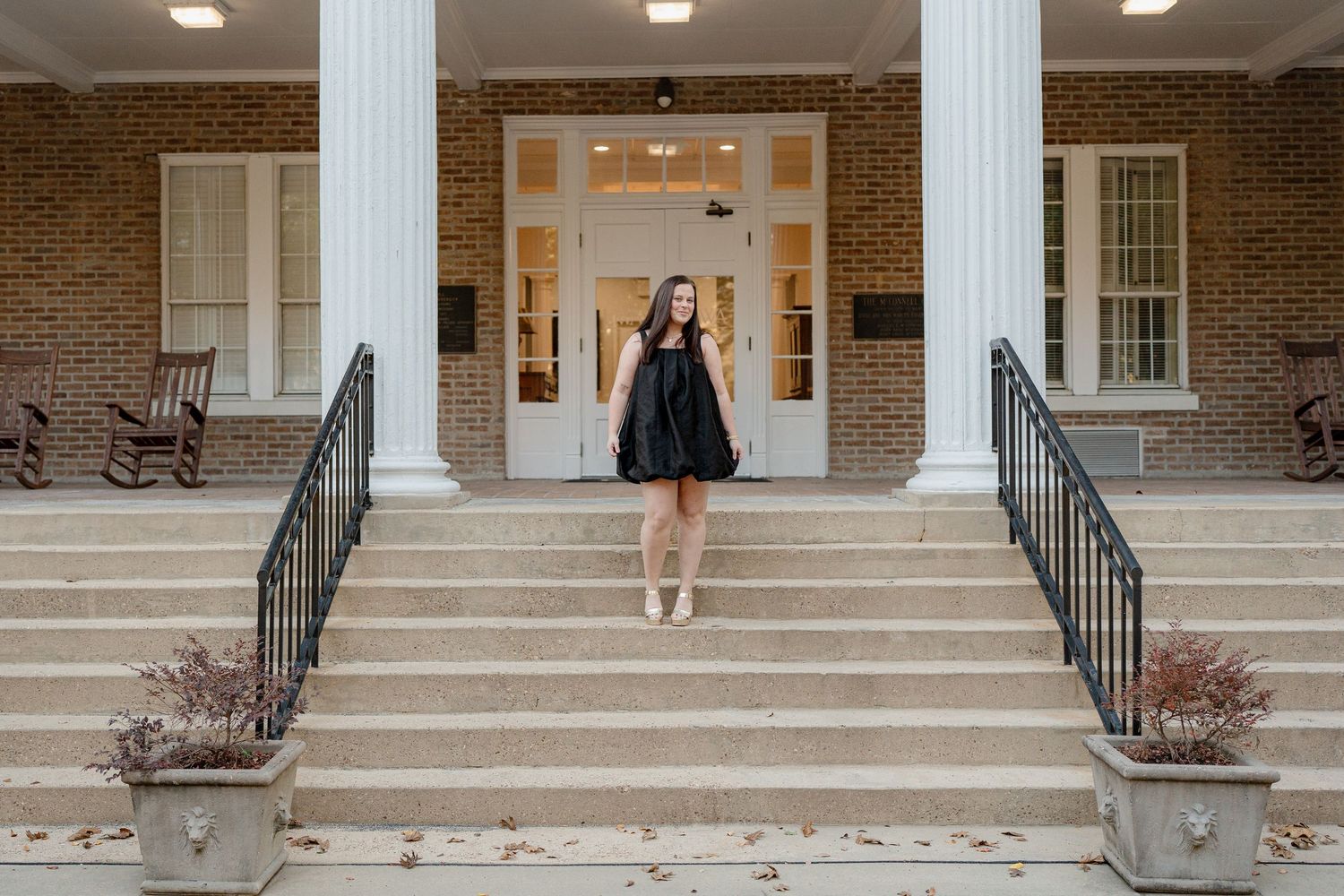 Students walk up and down concrete steps leading to the entrance of a brick university building.