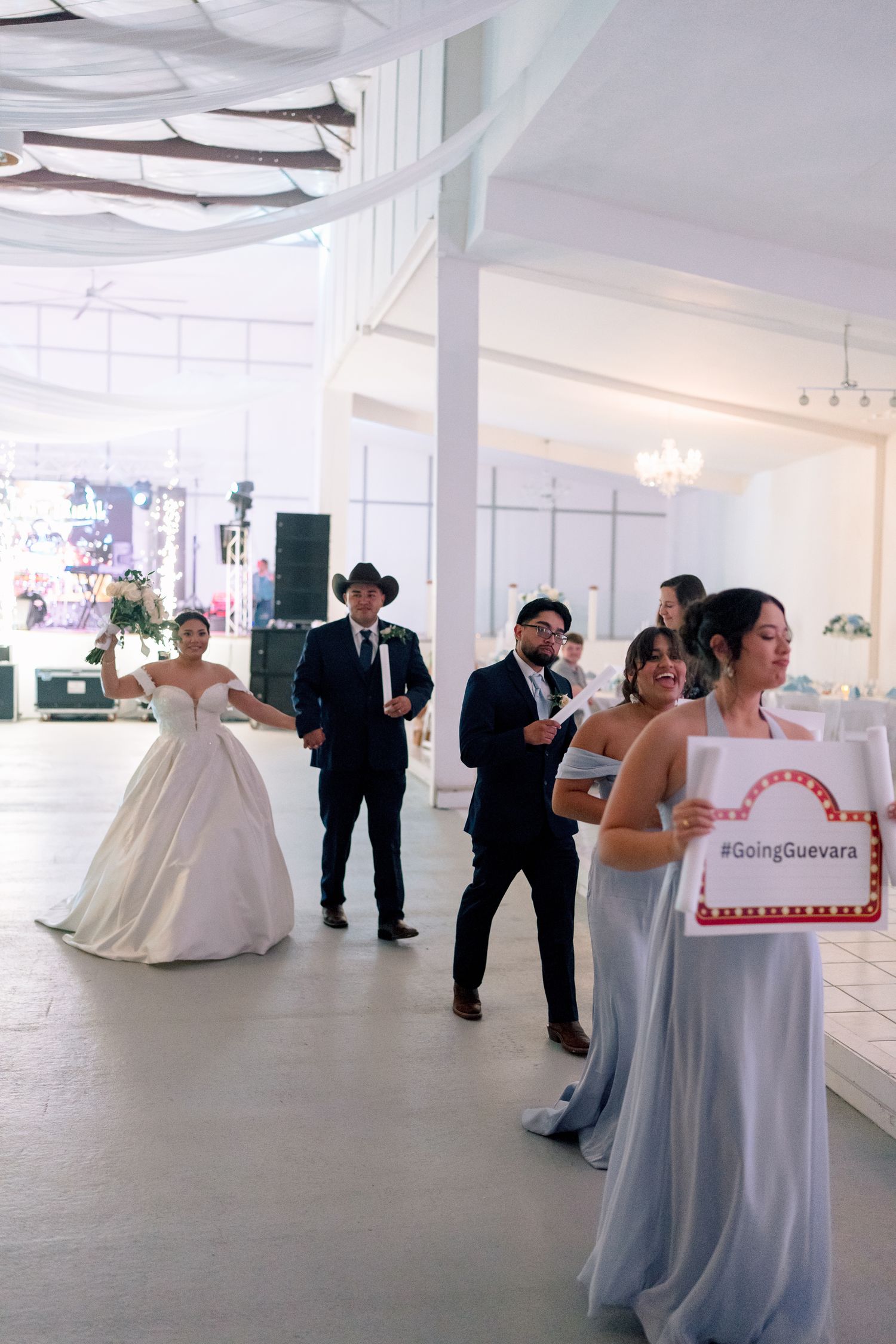 Wedding reception venue with elegant white decor and guests mingling in a bright modern space.
