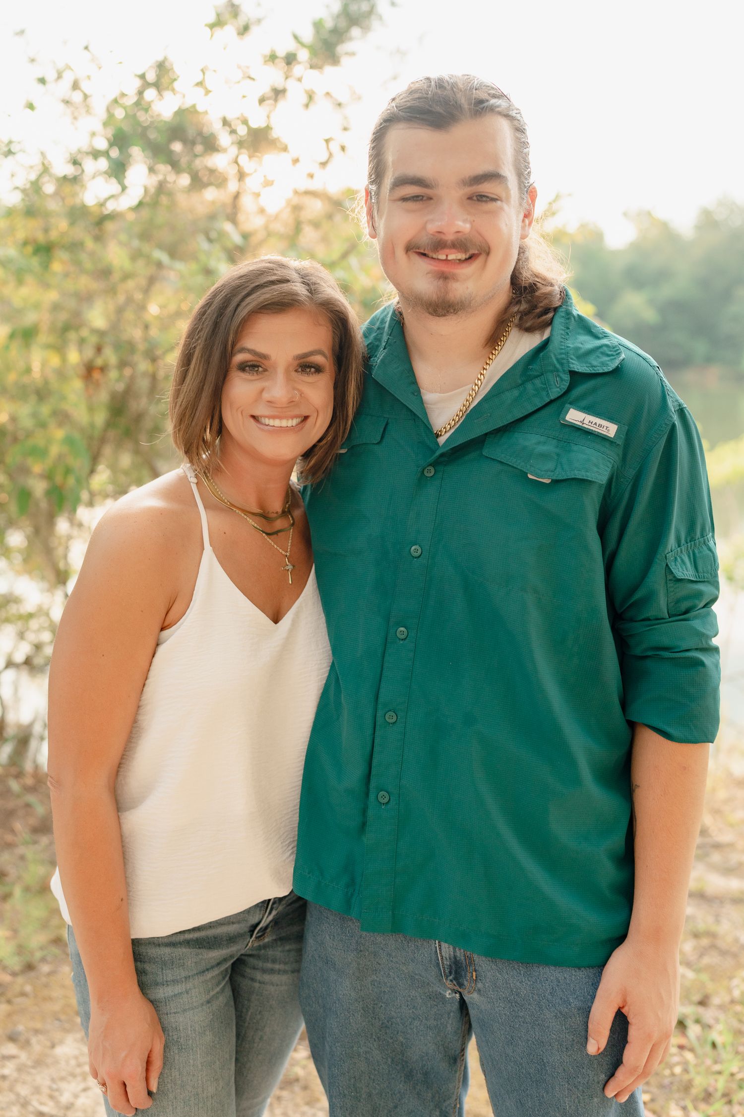 A couple shares tender moments together during a sunset photoshoot, wearing green and white outfits.