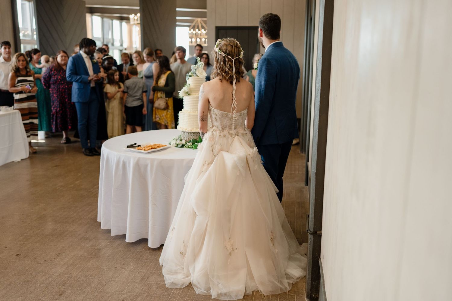 A couple shares their first dance at a wedding reception in an elegant indoor venue with guests watching.