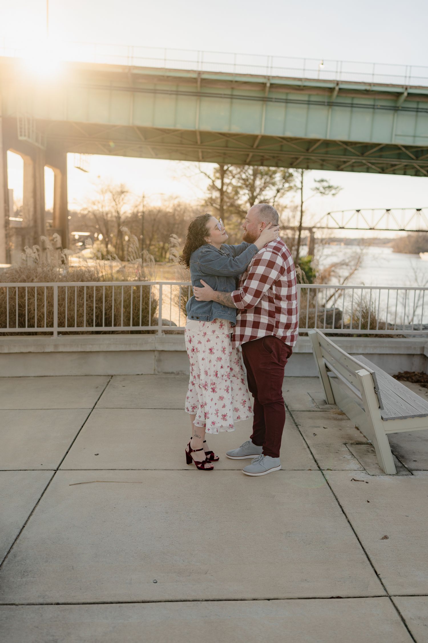 A romantic sunset photoshoot on a concrete pier overlooking a serene waterfront.