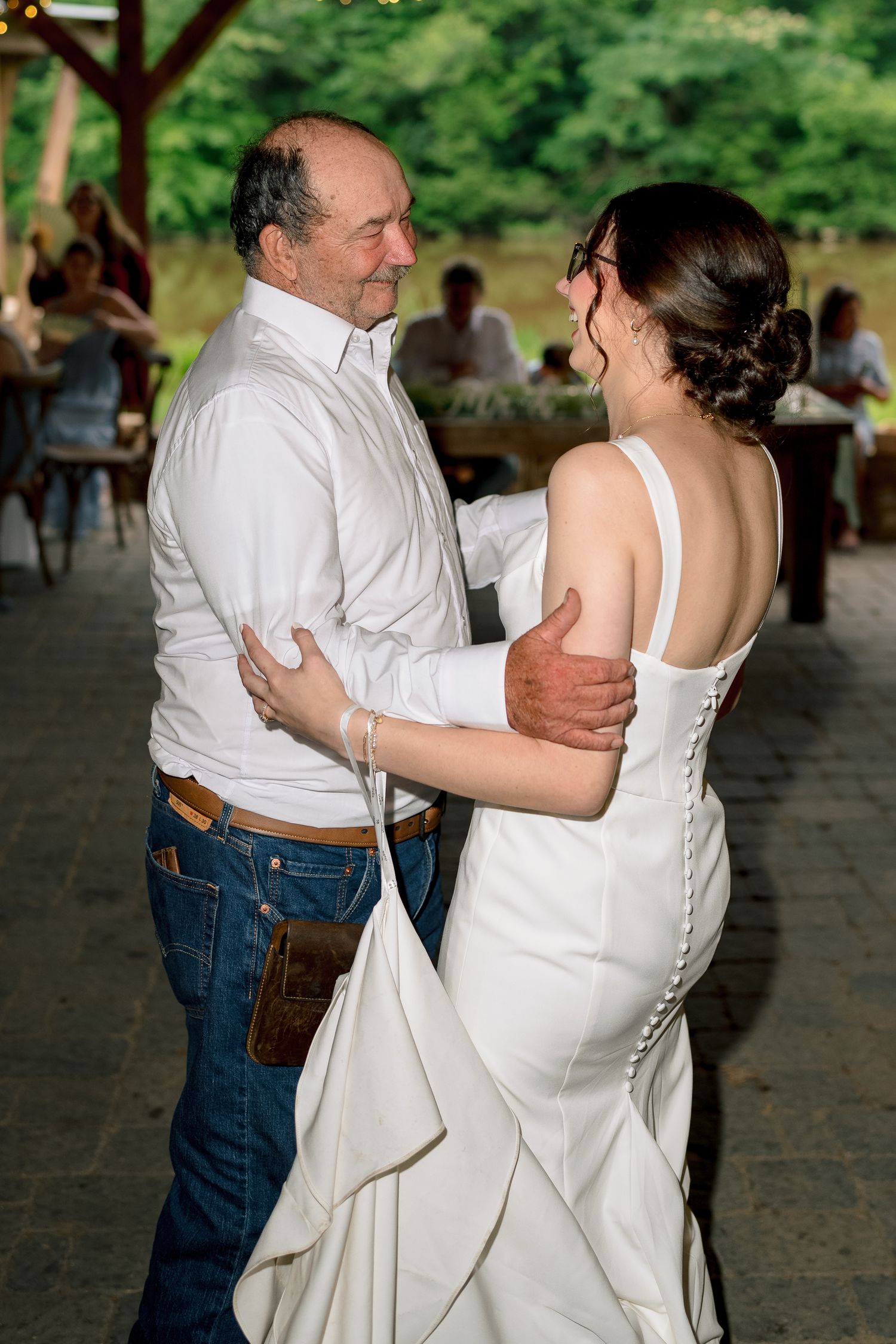 Bride and older man share a tender father-daughter dance at an outdoor wedding reception.