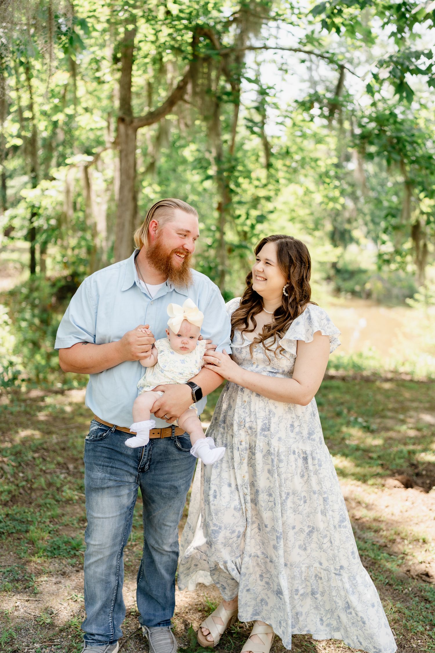 Candid family moments captured in a sun-drenched forest setting.
