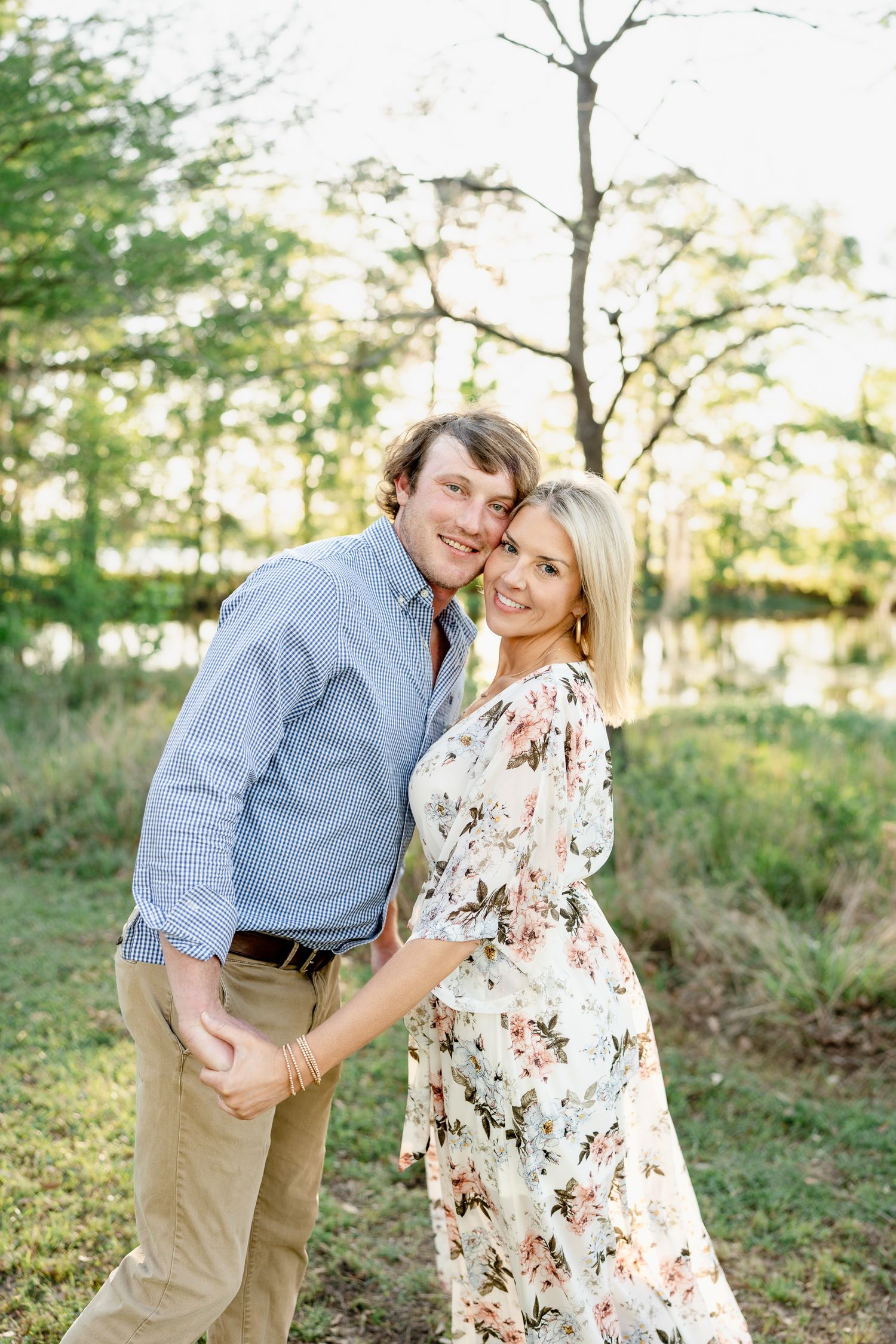 Happy couple sharing laughter during outdoor photo session in golden sunlight.