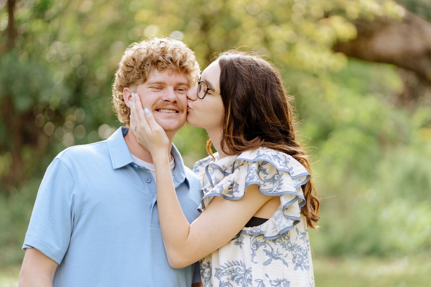 A romantic outdoor shoot in a garden showing a couple in casual attire kissing and embracing.