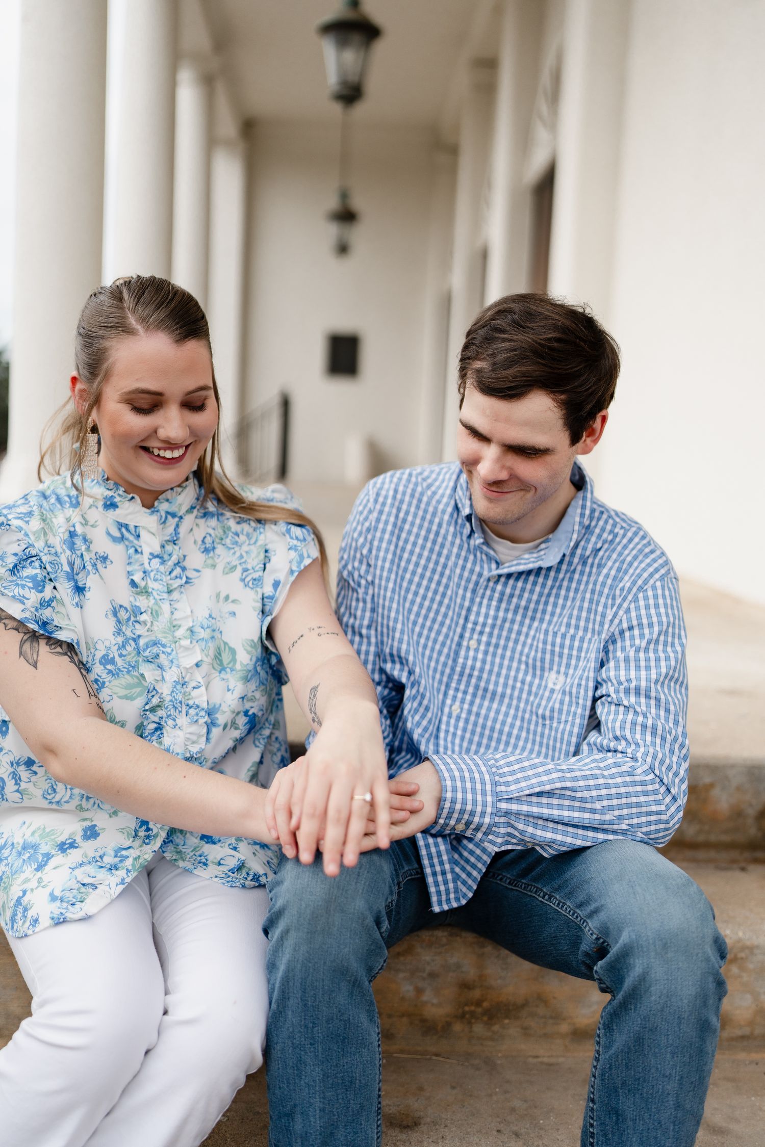 Couple shares intimate moments while sitting together on columned porch steps.