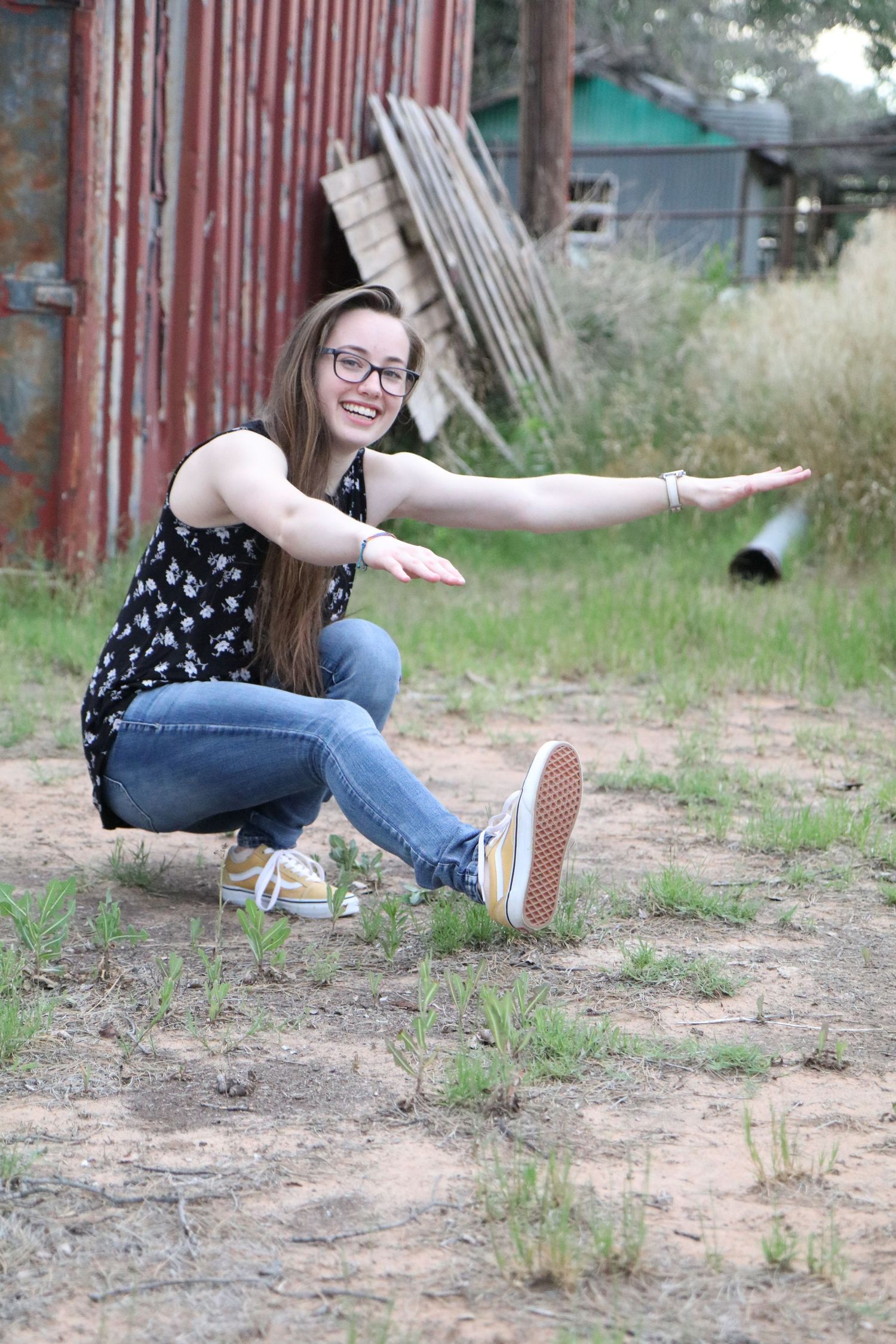 Playful outdoor pose on ground near rustic metal structure.