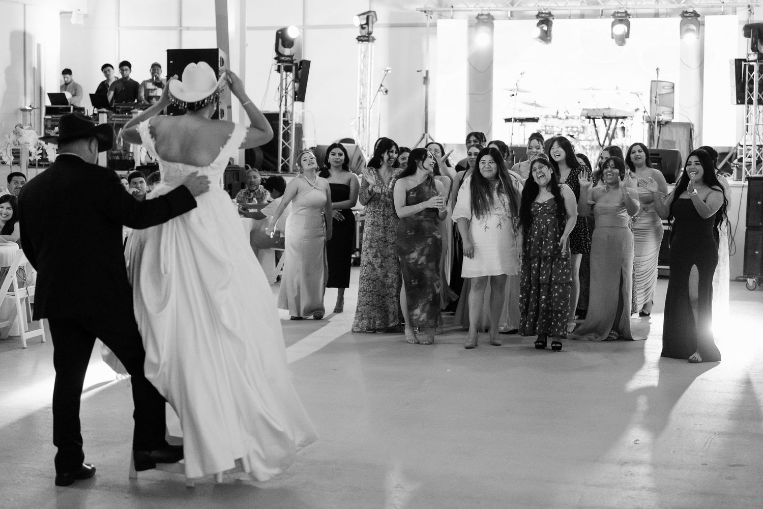 Wedding celebration with guests dancing and socializing in a spacious white reception hall.
