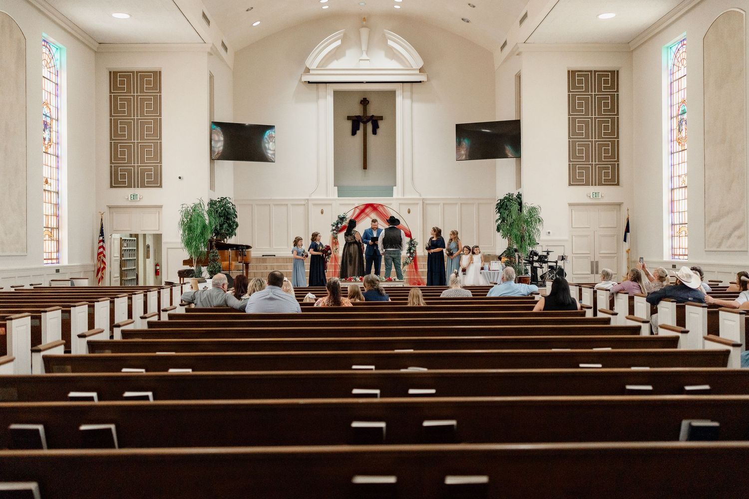 Interior view of a traditional church sanctuary with wooden pews and stained glass windows.