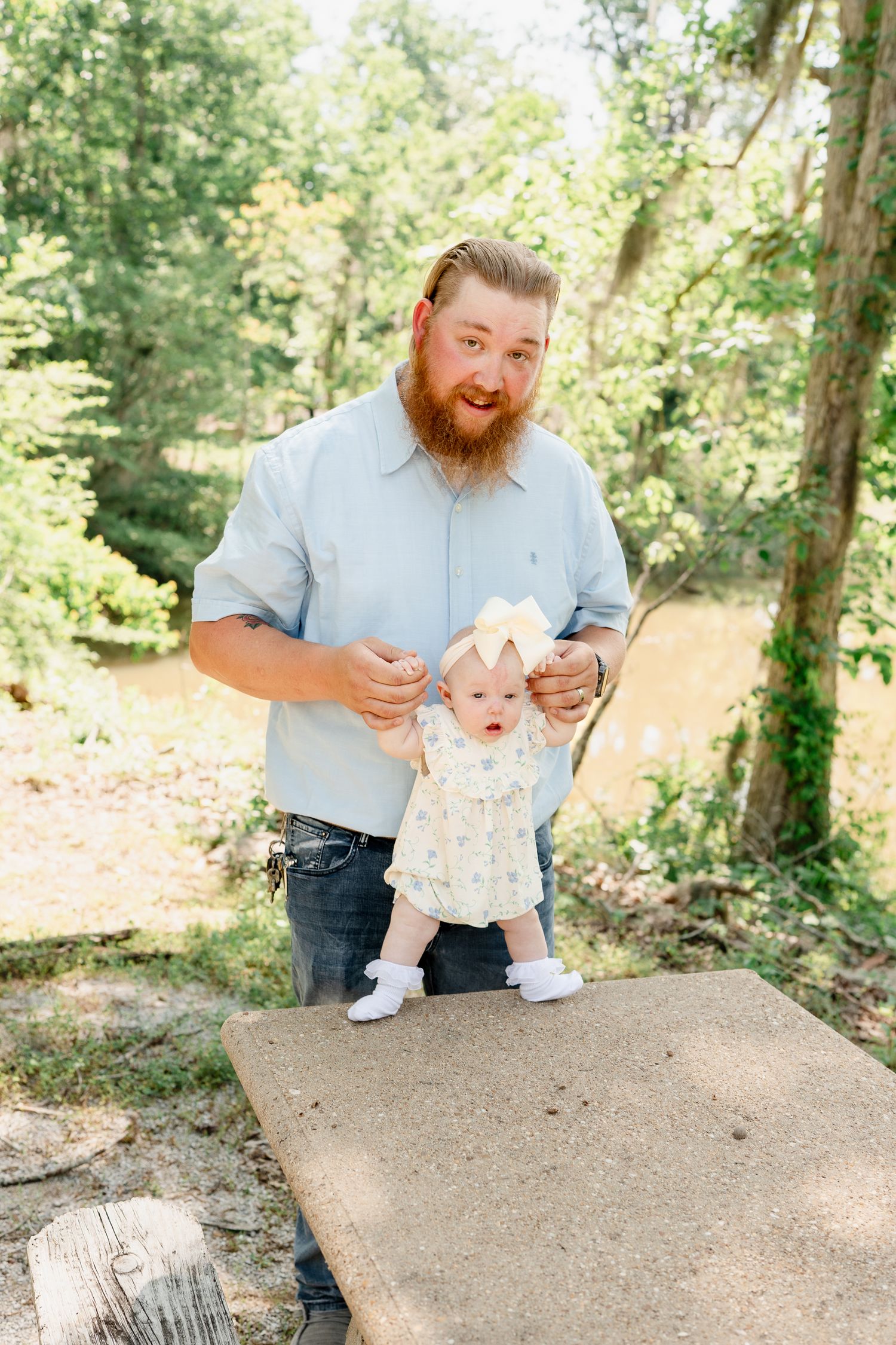 A sweet family moment captured outdoors in a natural wooded setting showing playful interaction on a concrete surface.