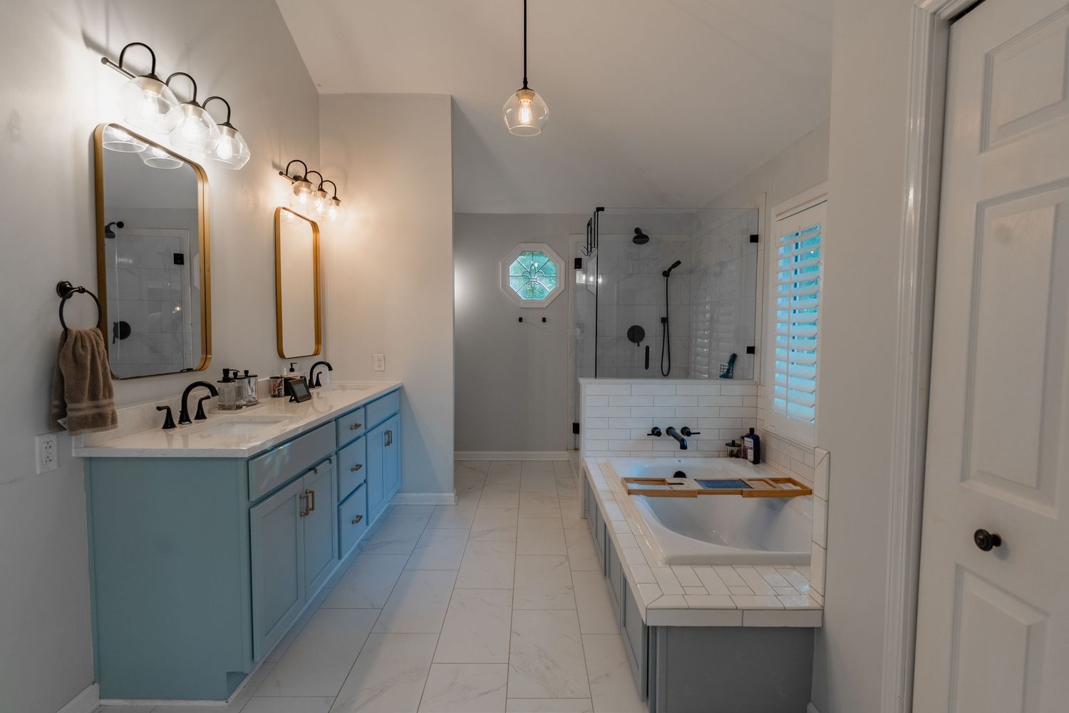 Contemporary bathroom featuring white vanity, blue walls, and chrome fixtures with natural lighting.