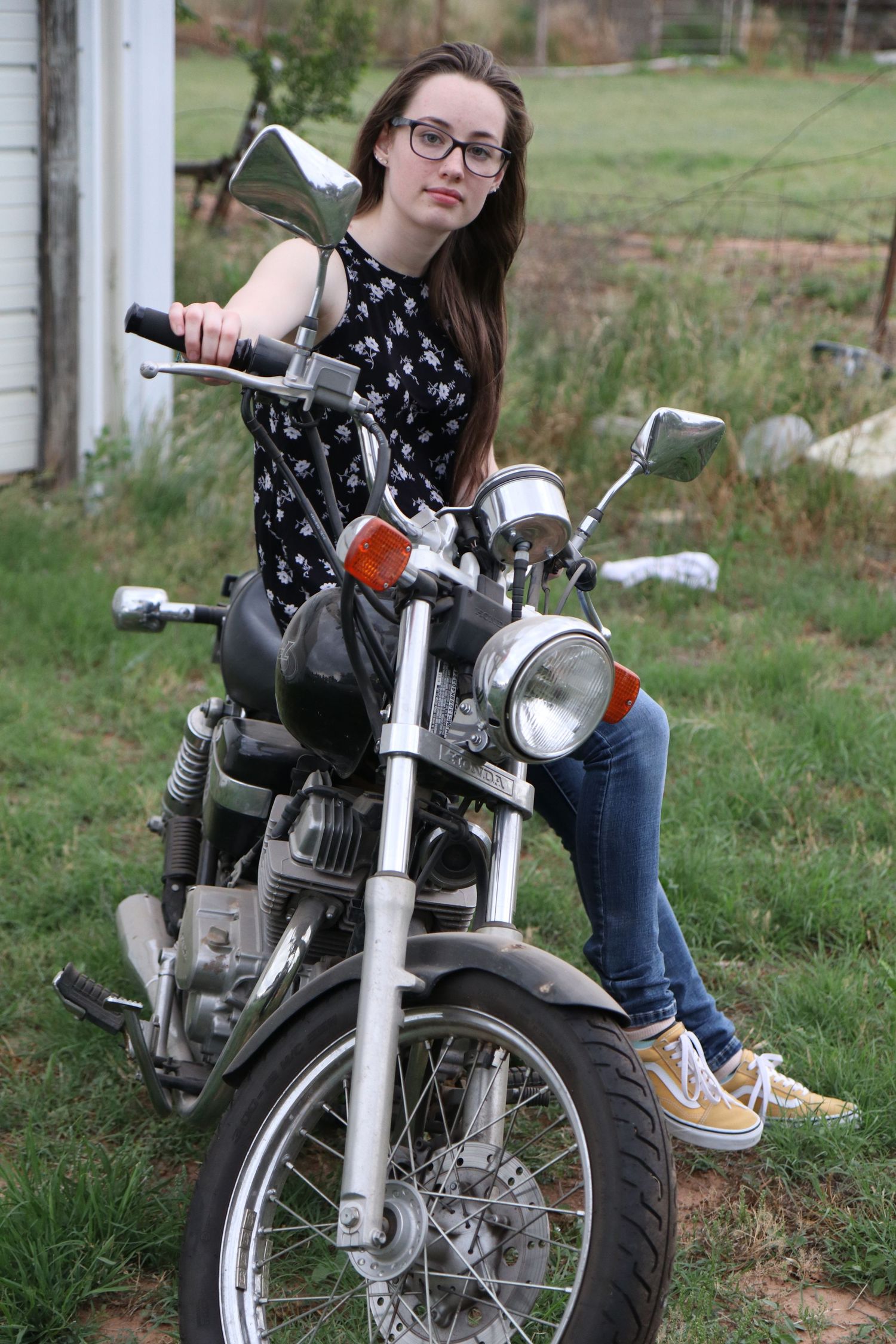 Classic motorcycle parked in grassy field with detailed front view of chrome and headlight.
