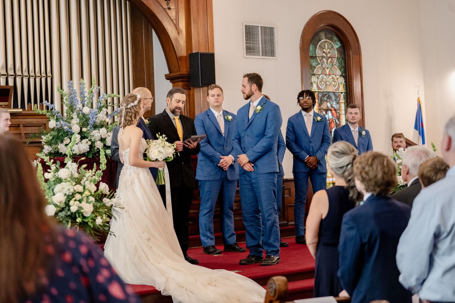 Multiple frames capture a wedding ceremony in a church with guests in blue attire and floral decorations.
