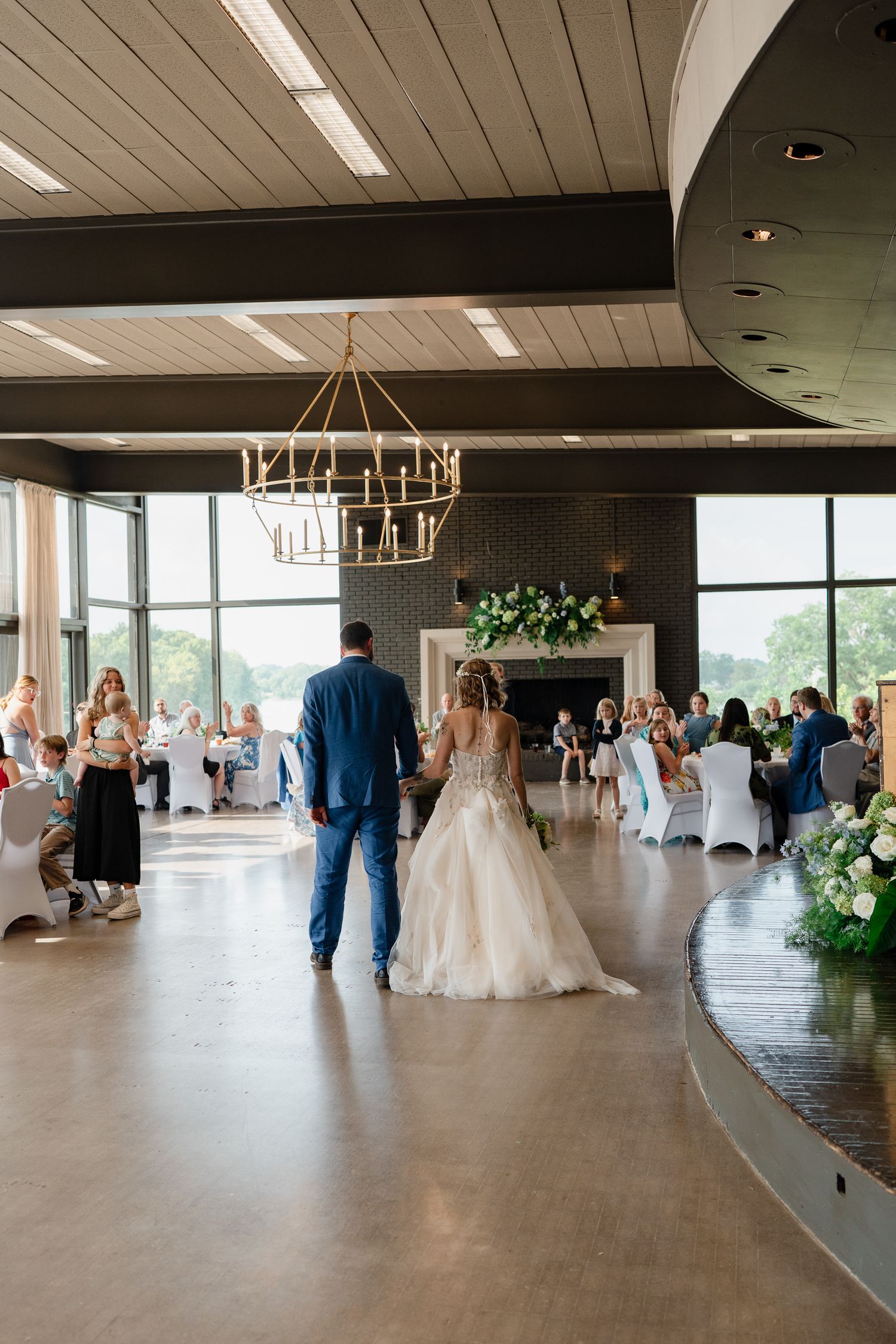 Panoramic view of a modern wedding reception venue with white chairs and decorative lighting.